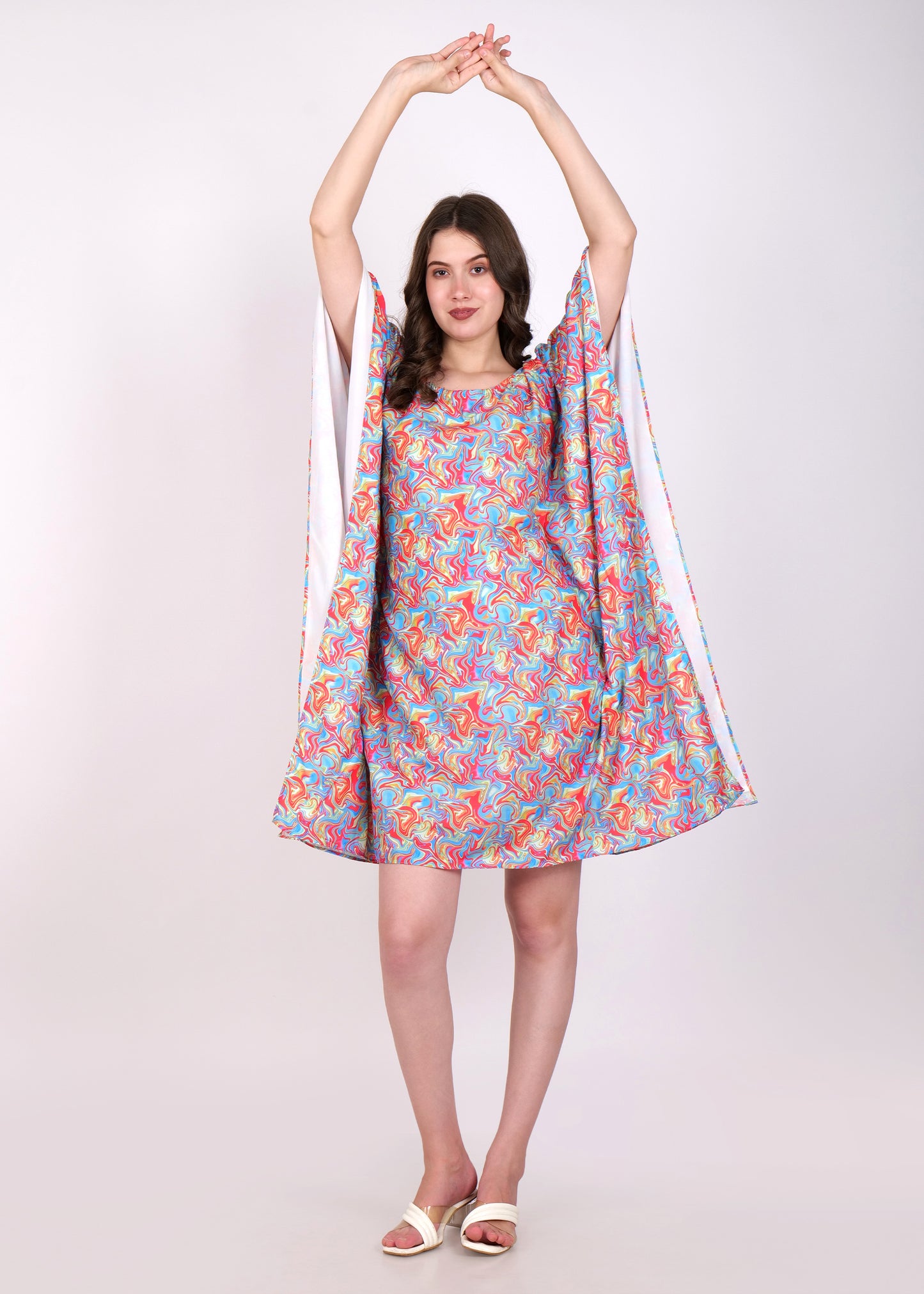 Woman wearing colorful kaftan dress with flowy sleeves, posing with arms raised, perfect for summer fashion