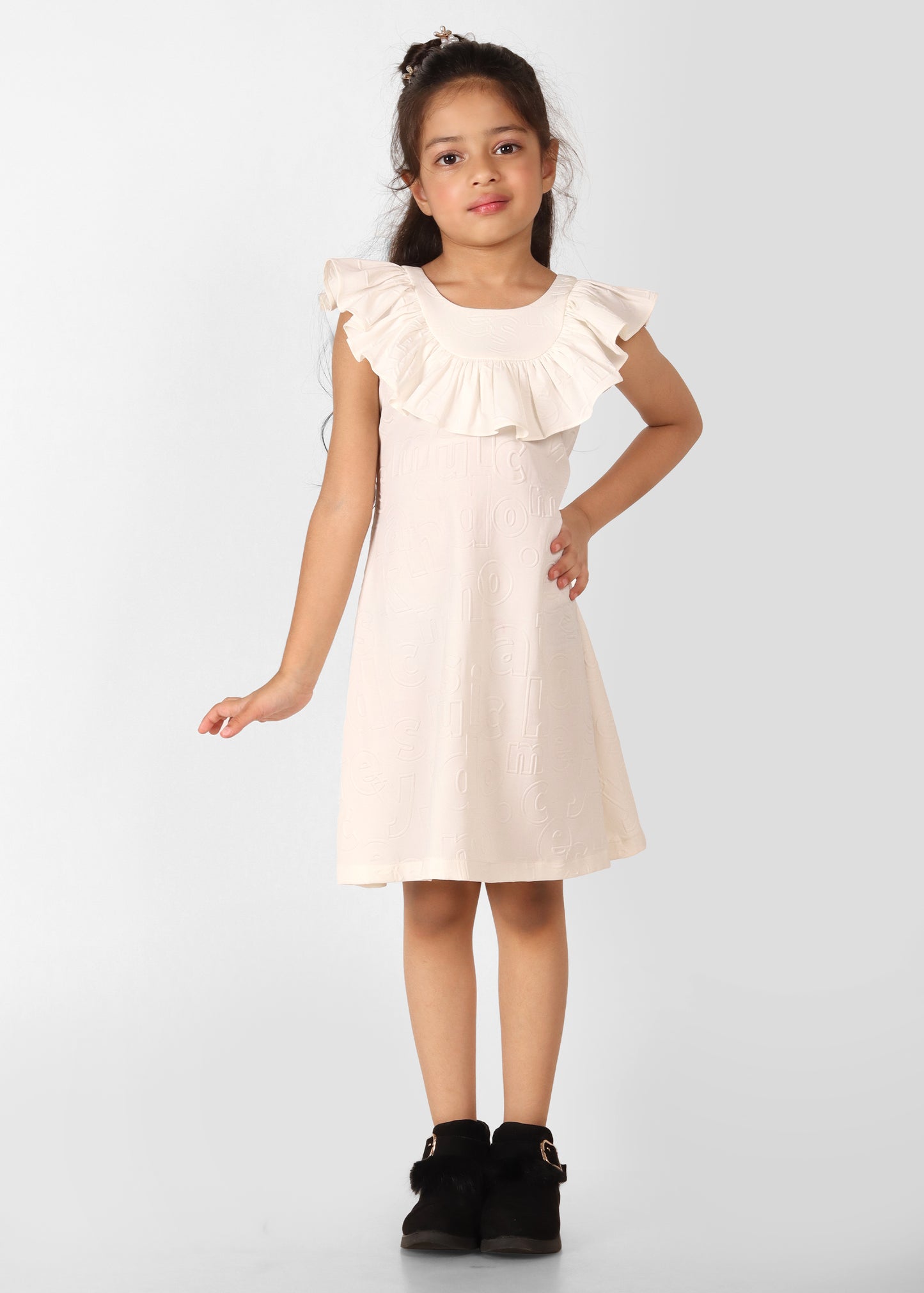 Girl wearing a cream ruffle-sleeve dress paired with black fur-trimmed ankle boots, standing confidently