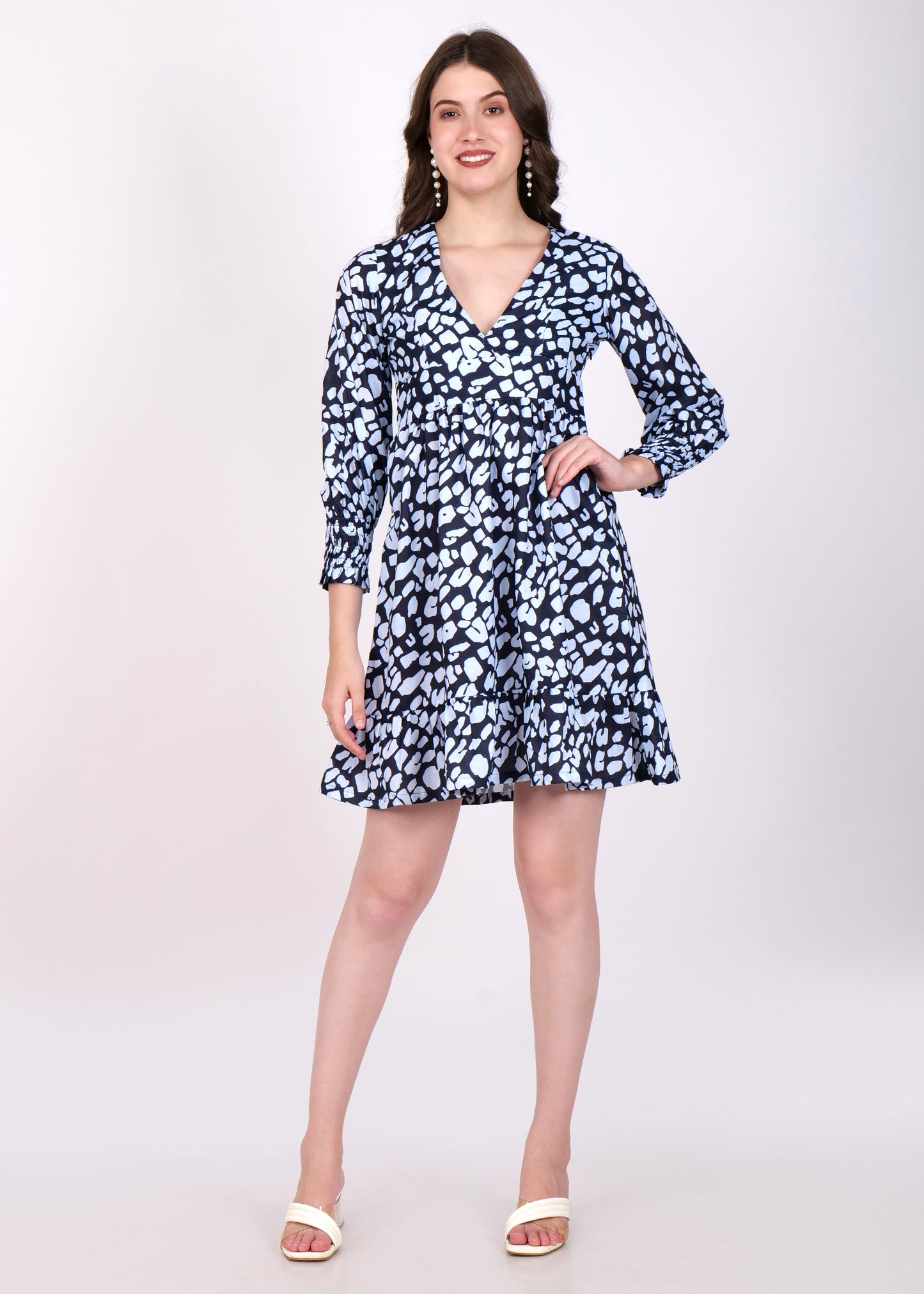 Model wearing a chic navy blue printed dress with white abstract patterns, featuring a deep V-neckline and long sleeves, perfect for a casual outing