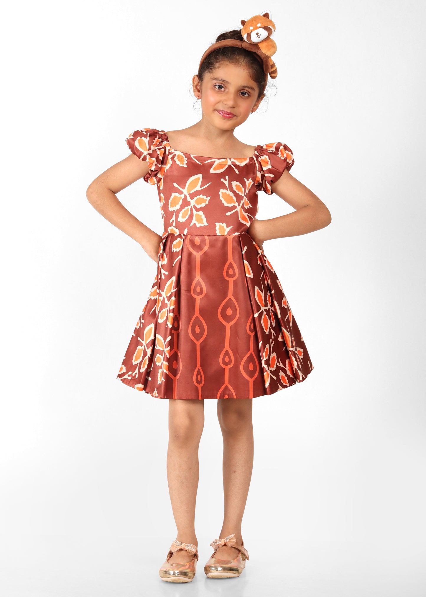 Little girl wearing a floral brown dress with puffed sleeves and pleated skirt, accessorized with a cute headband and sunglasses, posing confidently