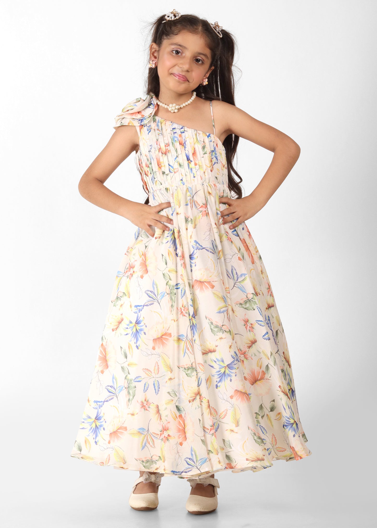 Girl wearing a floral printed off-shoulder gown with colorful flowers and a pleated bodice, holding a stuffed tiger