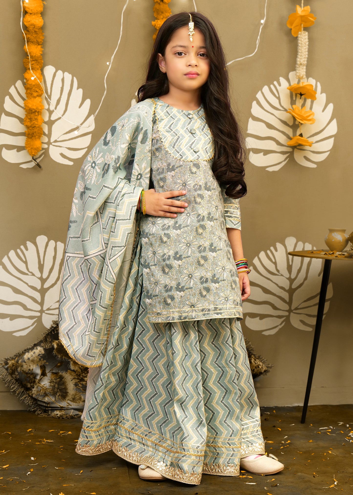 "Girl wearing a pastel green traditional Indian outfit with floral embroidery and chevron print palazzo pants."