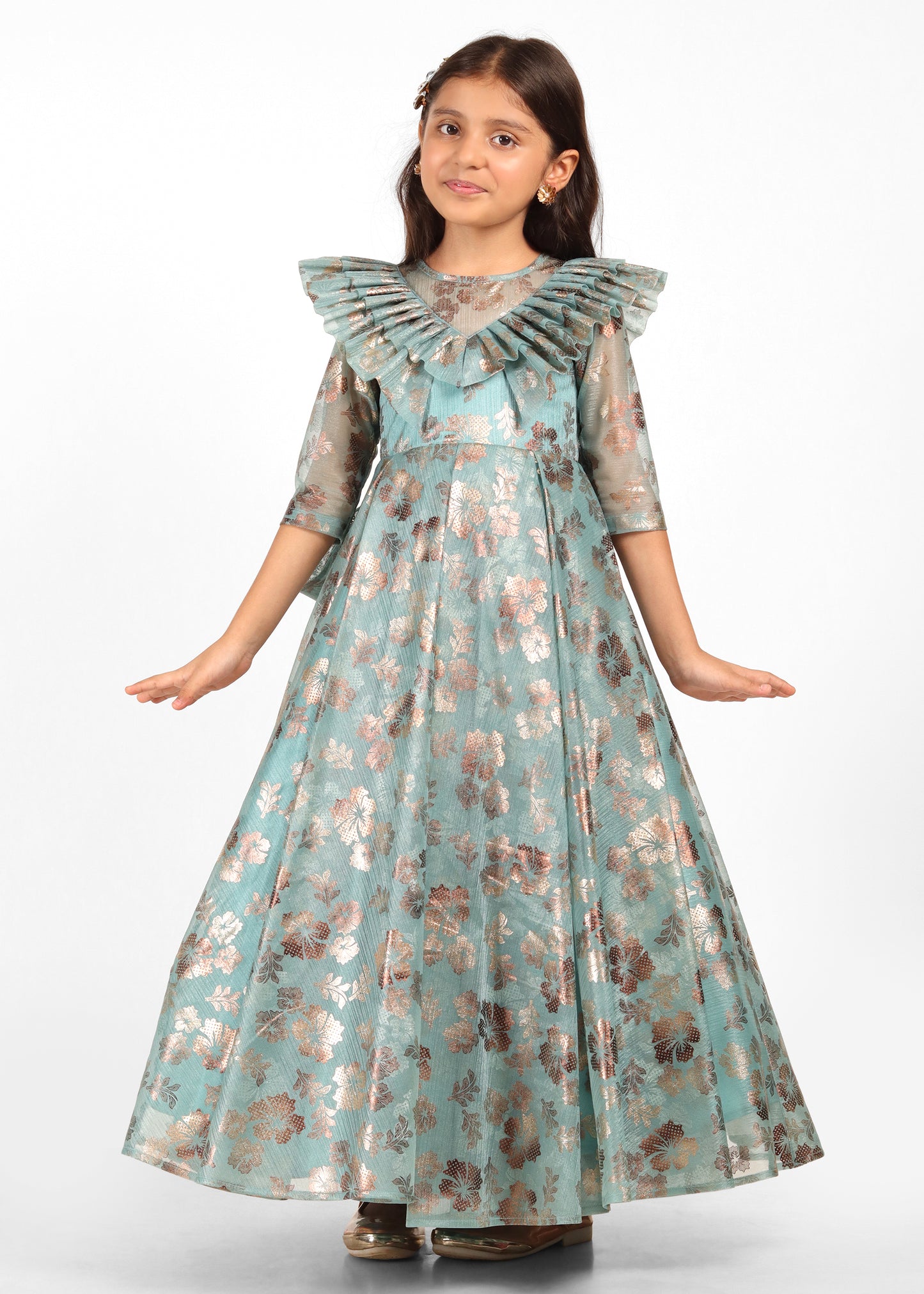 Young model in a full teal gown with gold floral embroidery, showcasing a glamorous side pose with a bow detail at the back.
