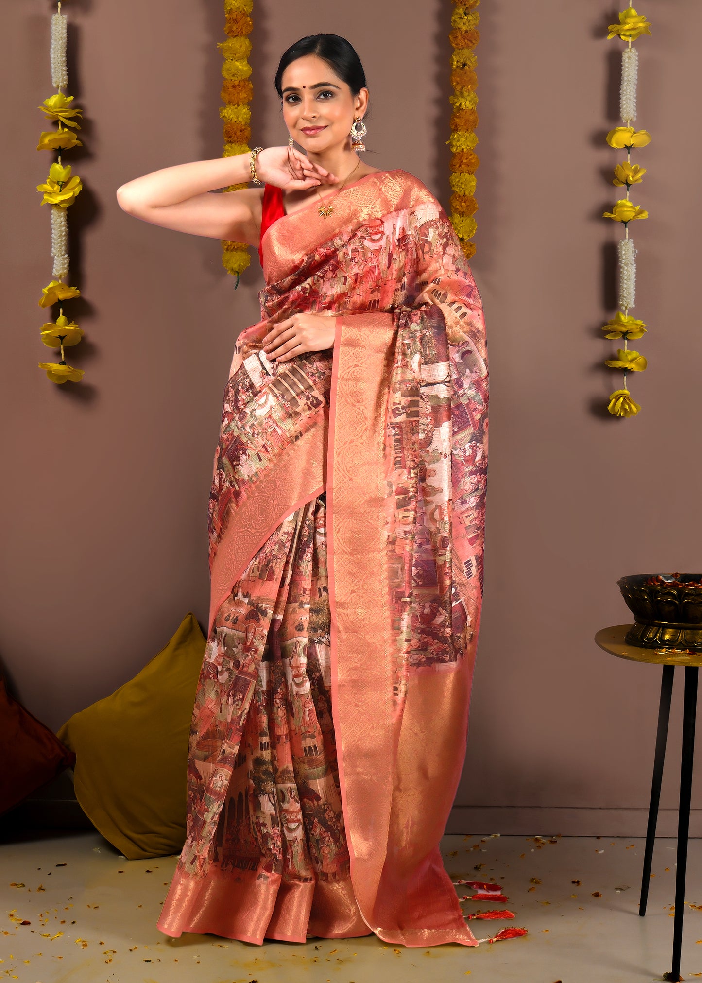 Elegant peach saree with cityscape motifs worn by a model, complemented by gold zari work and subtle pleats.