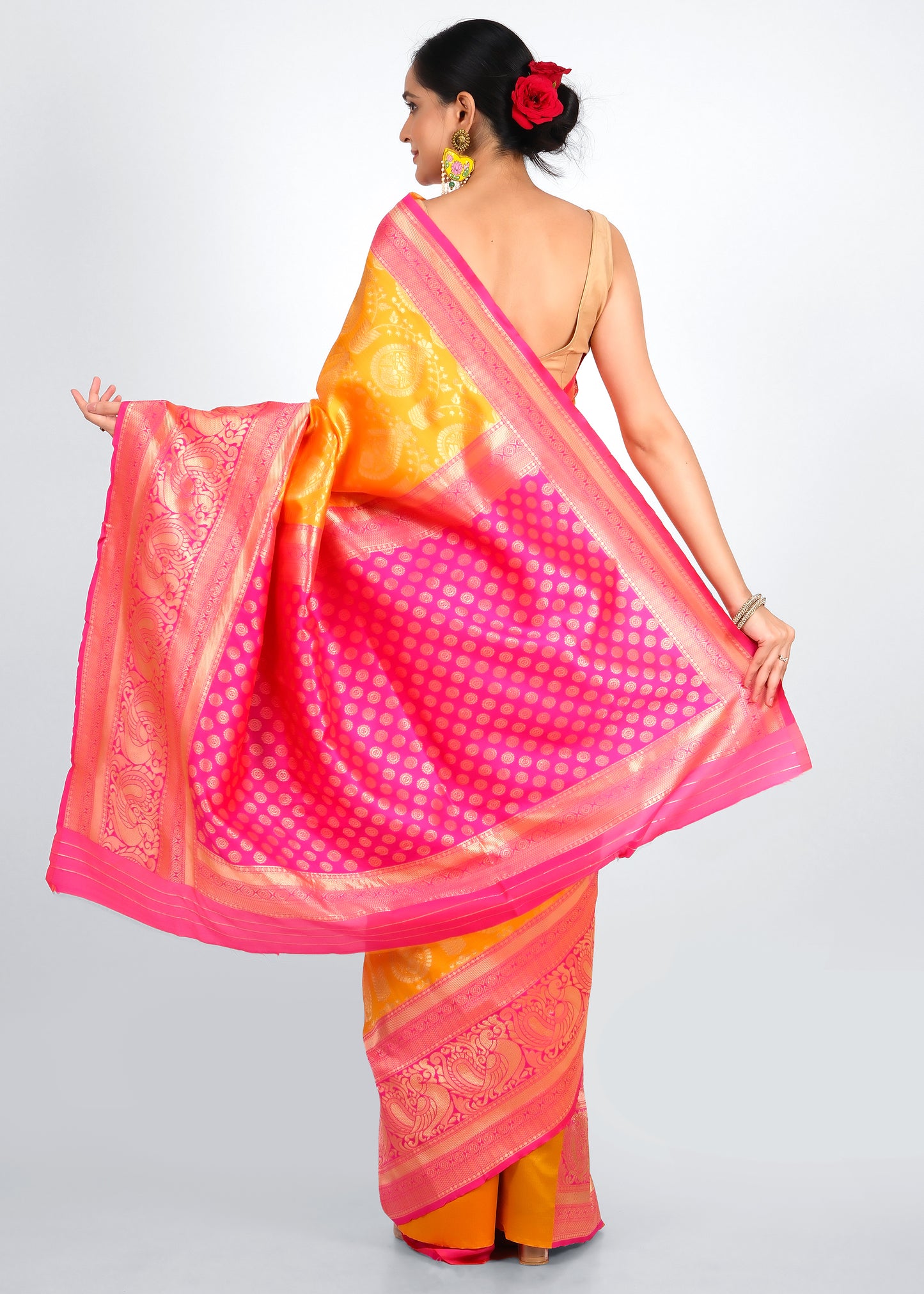 Rear view of a traditional orange silk saree with a pink polka-dotted pallu, highlighting the contrasting colors and intricate detailing