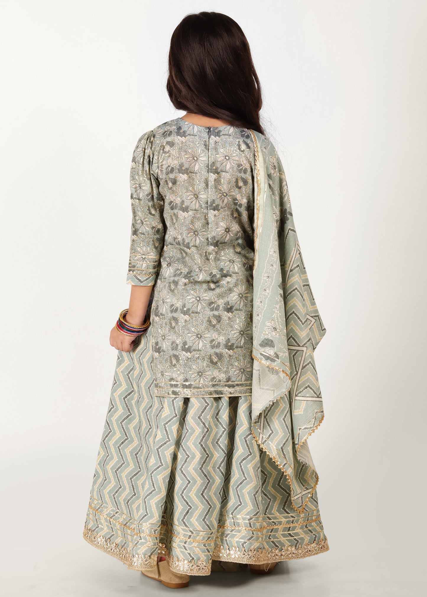 "Back view of a girl in a traditional light green embroidered kurta with detailed flower patterns, paired with a zigzag palazzo and matching dupatta."