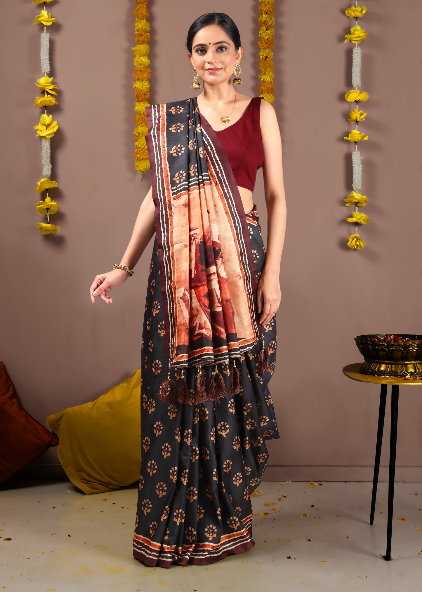 Elegant Indian woman posing in a black saree with artistic pallu print and floral patterns, paired with a sleeveless maroon blouse