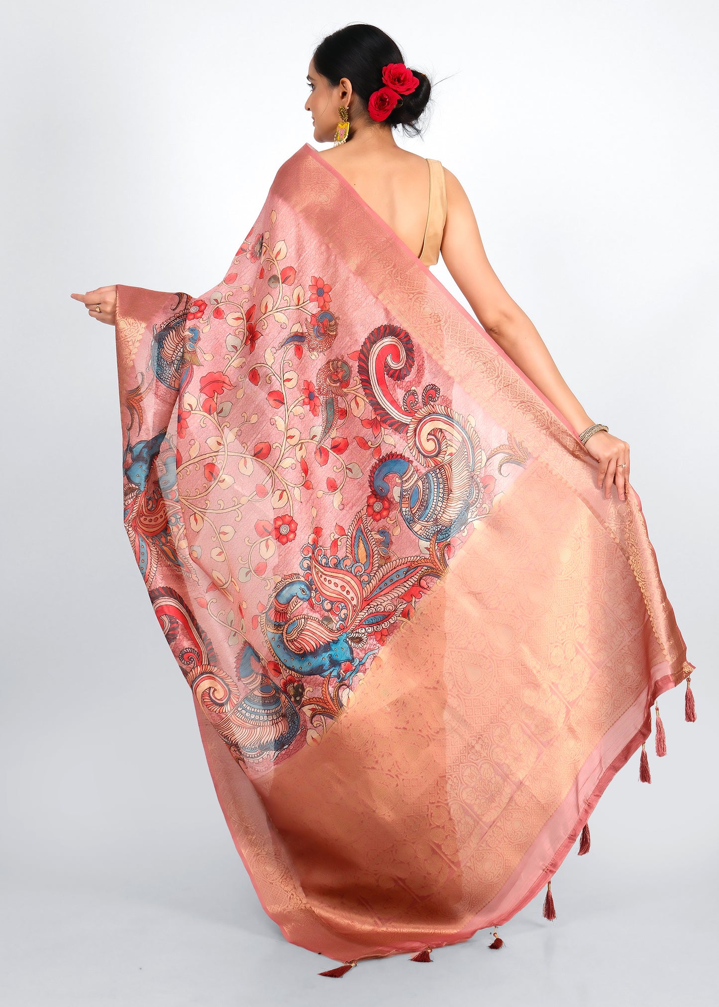 Close-up of a luxurious pink silk saree featuring golden borders and colorful peacock motifs, highlighting the detailed craftsmanship.