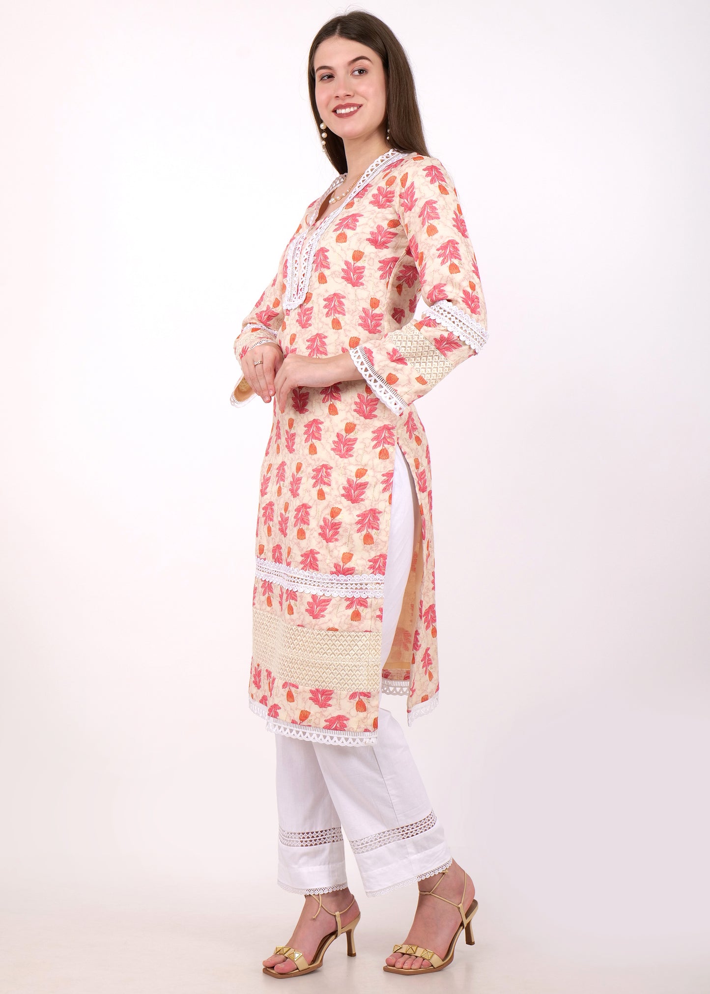 Side view of a woman wearing a beige and pink floral kurta set with lace detailing, paired with white pants