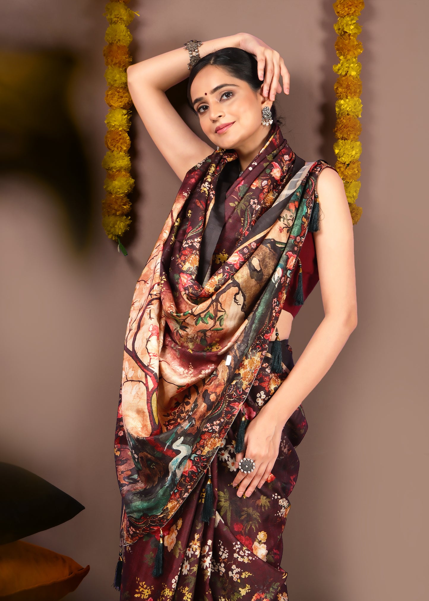 Close-up of model wearing a maroon floral saree with draped pallu, showcasing detailed prints and textures in traditional attire