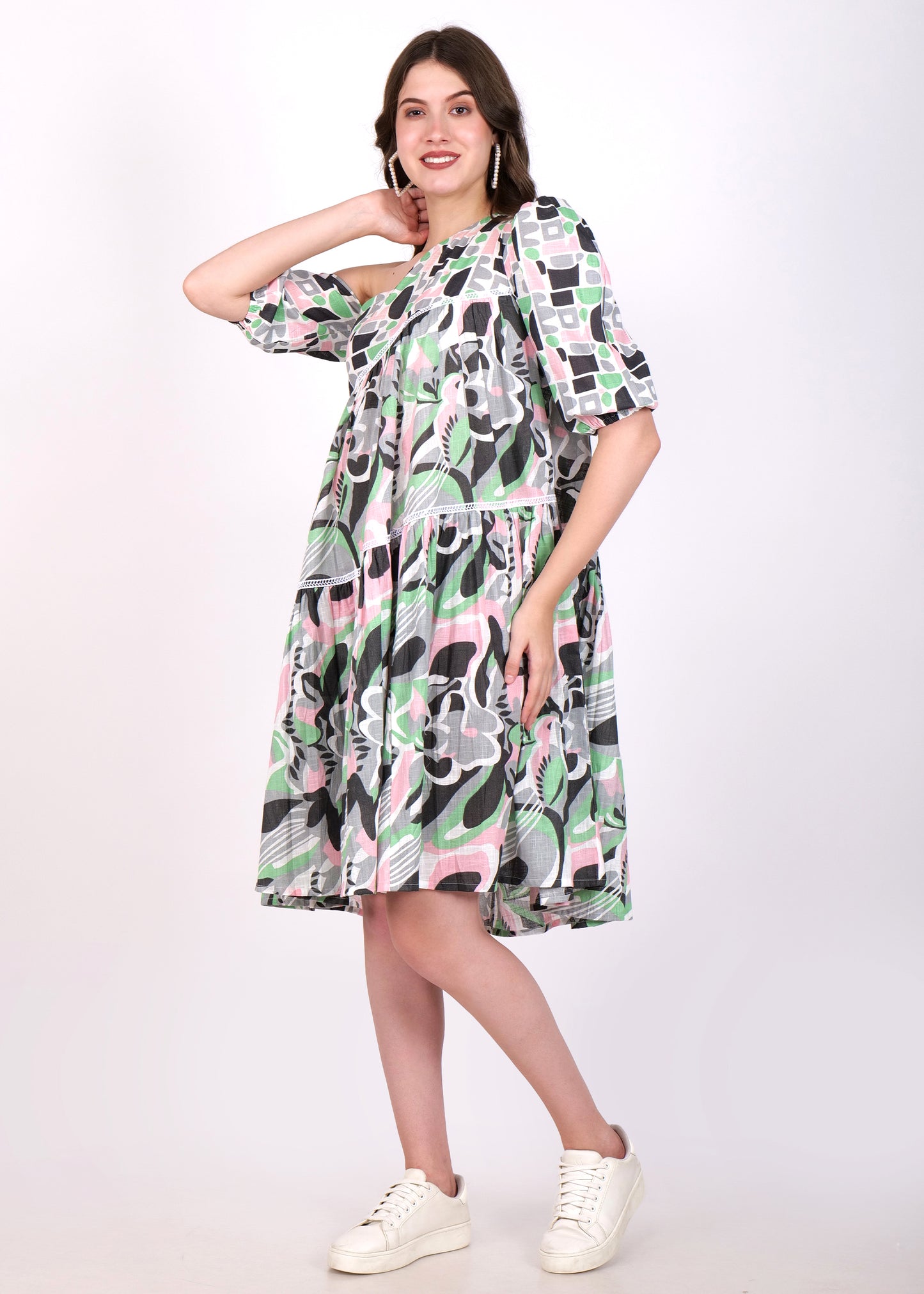 Stylish woman wearing a geometric patterned one-shoulder dress, casually adjusting her hair.