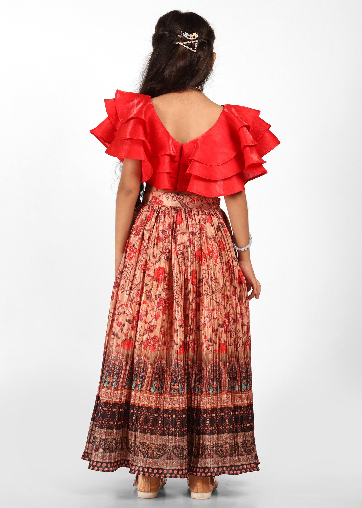 Back view of a girl in a flowy long skirt with floral designs and a bold red ruffled top, showing off her hairstyle and chic look.