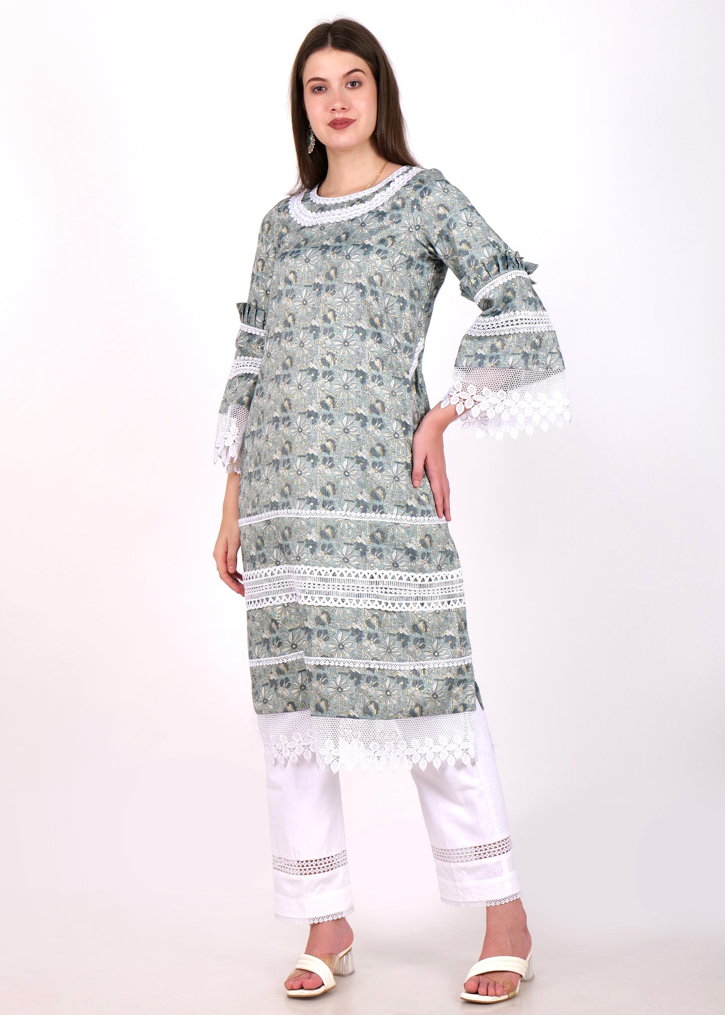 Fashionable woman in a floral-printed green kurta and white pants, featuring intricate lacework and bell sleeves, striking a side pose.