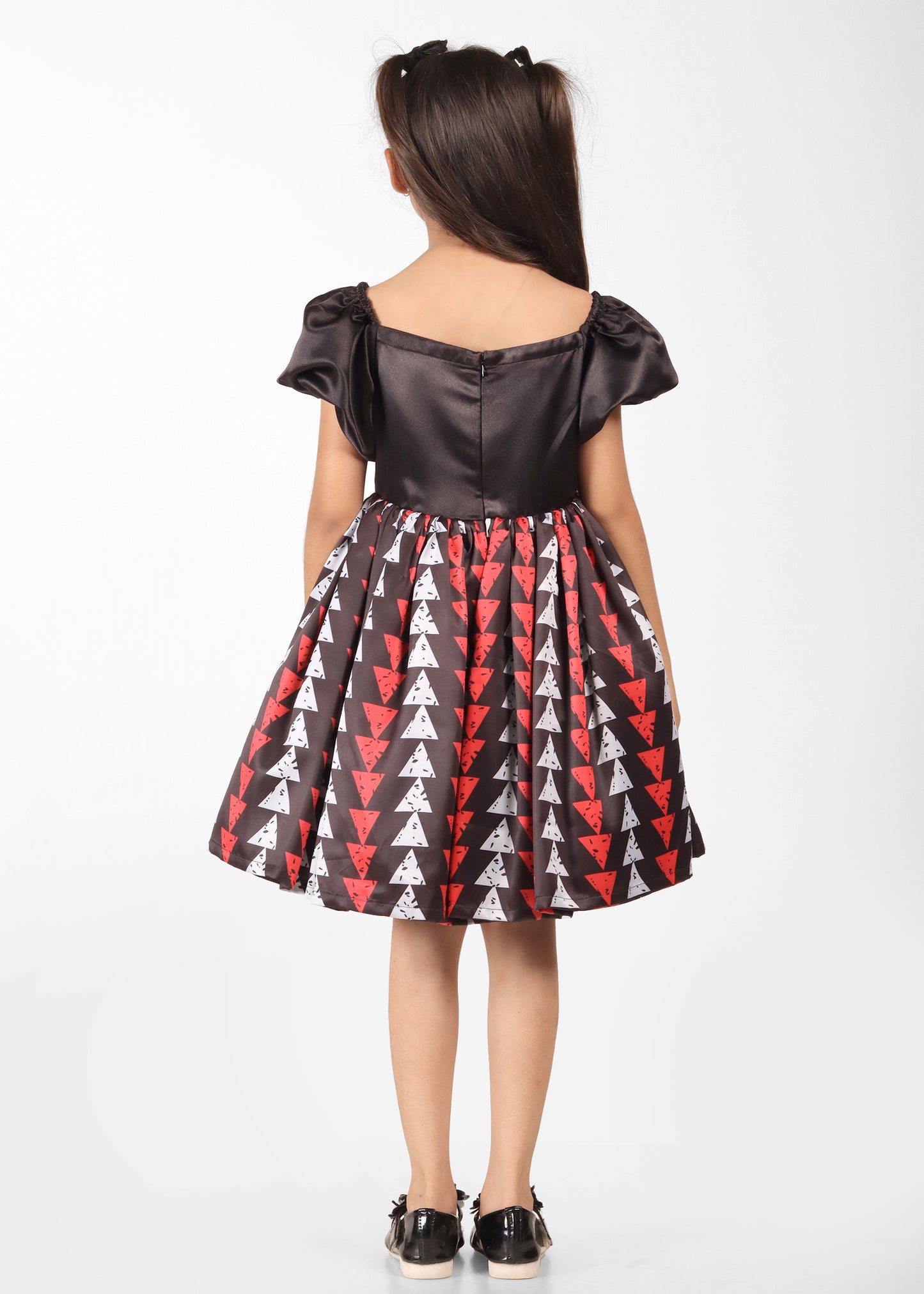 Back view of a girl in a black satin dress with red and white geometric patterns