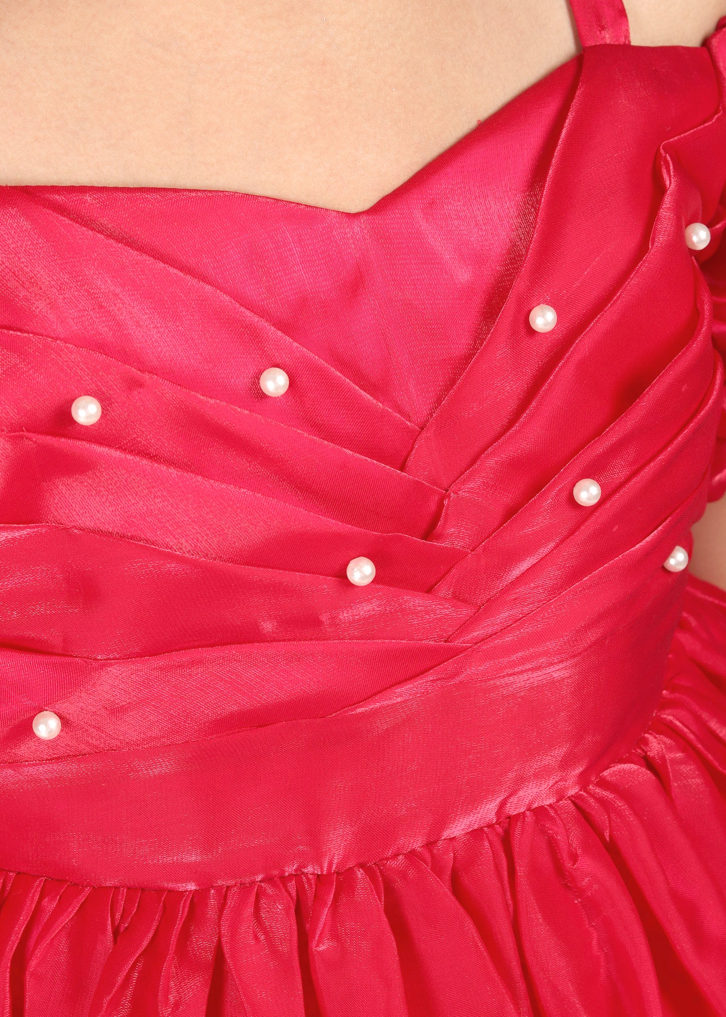 "Detailed close-up of the red dress featuring pearl embellishments and neatly folded pleats on the bodice, showcasing the premium craftsmanship."