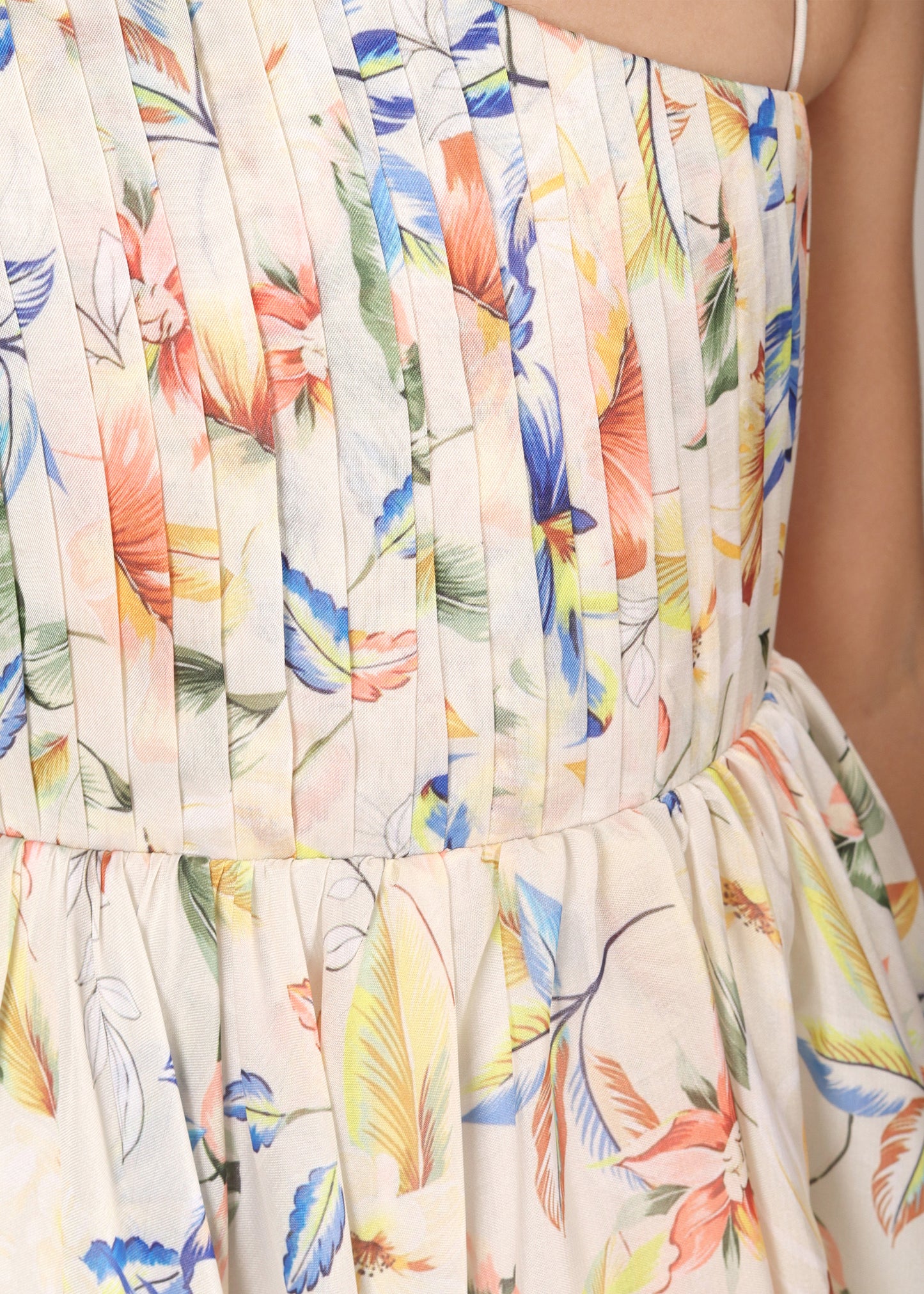 Close-up of a floral printed gown's pleated bodice with multicolored flowers, showcasing intricate fabric design.