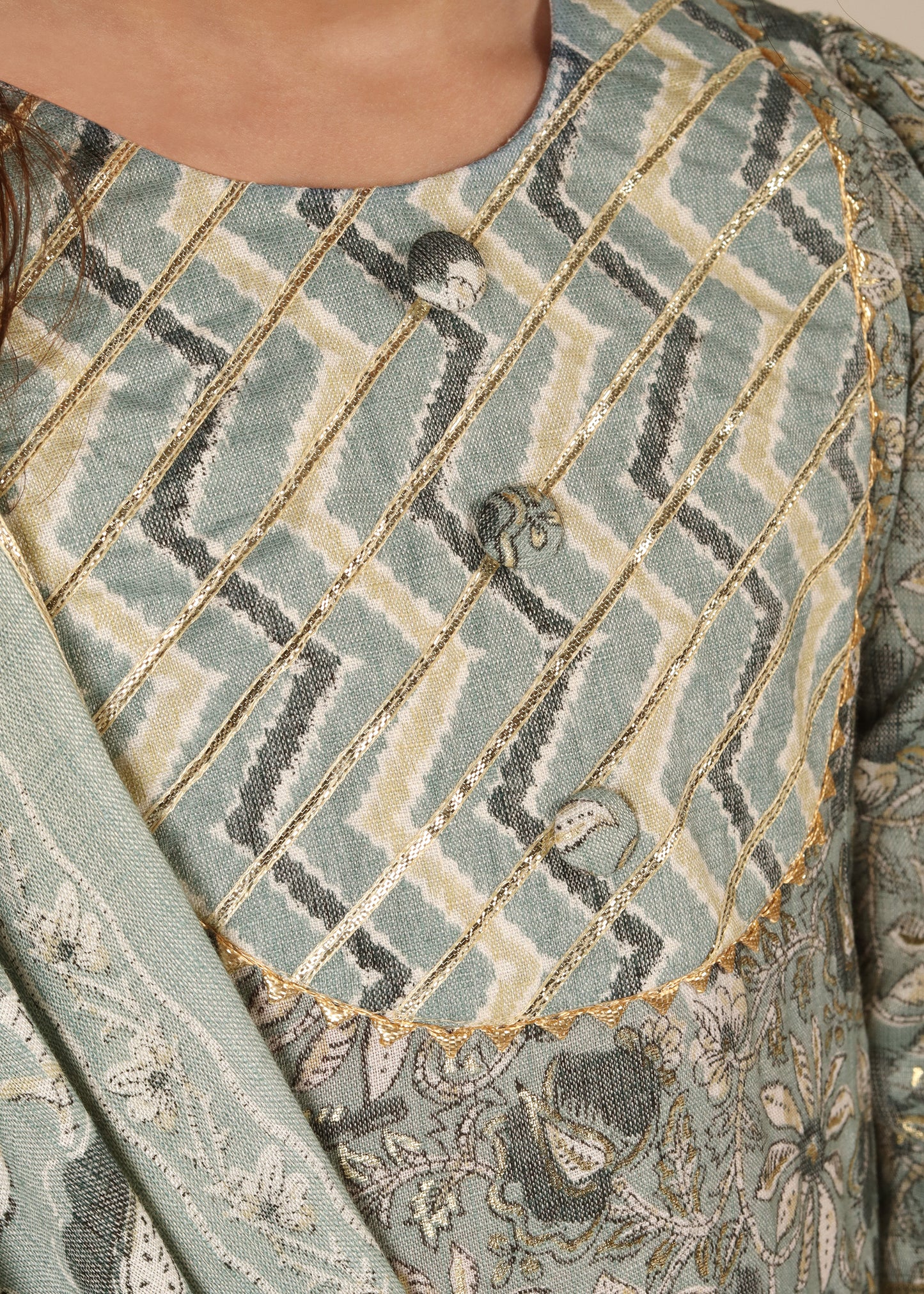 "Close-up of intricate golden and silver embroidery on a light green ethnic kurta with zigzag detailing on the neckline."
