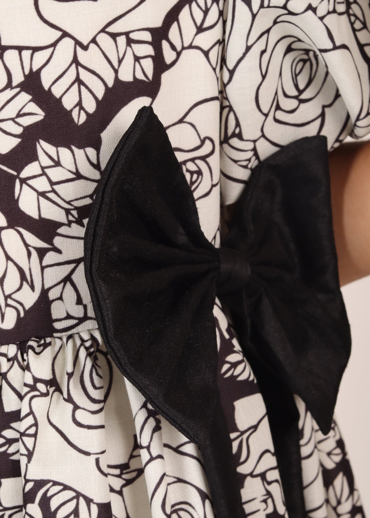 Close-up of the black bow and floral pattern on a girl's black and white dress, focusing on the intricate design and fabric details, perfect for stylish children's outfits