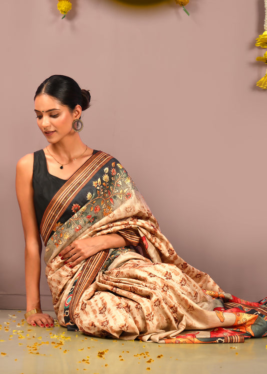 Elegant woman sitting in a beige saree with floral designs and vivid animal prints, styled for a festive or cultural event.
