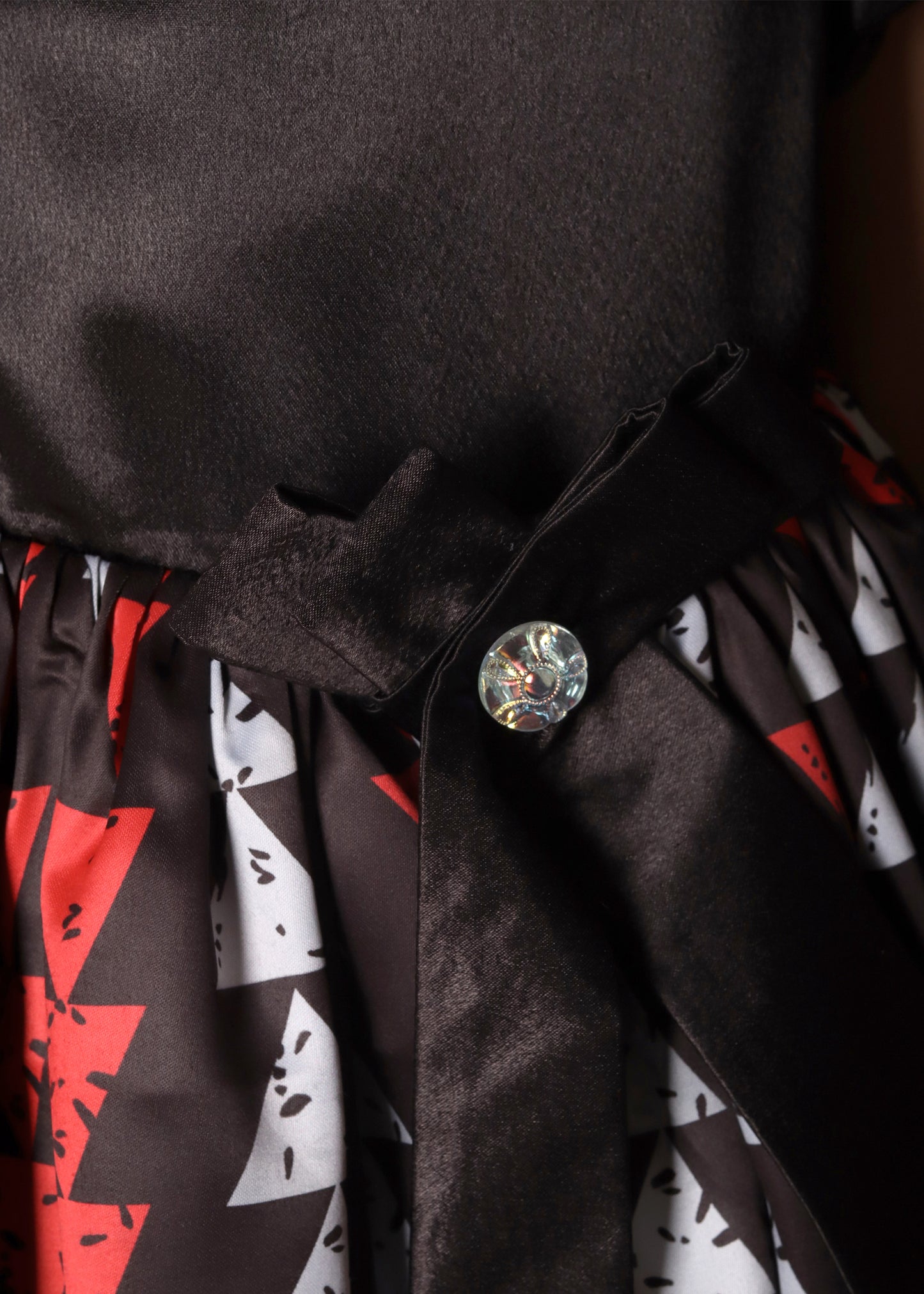 Back view of a girl in a black satin dress with red and white geometric patterns
