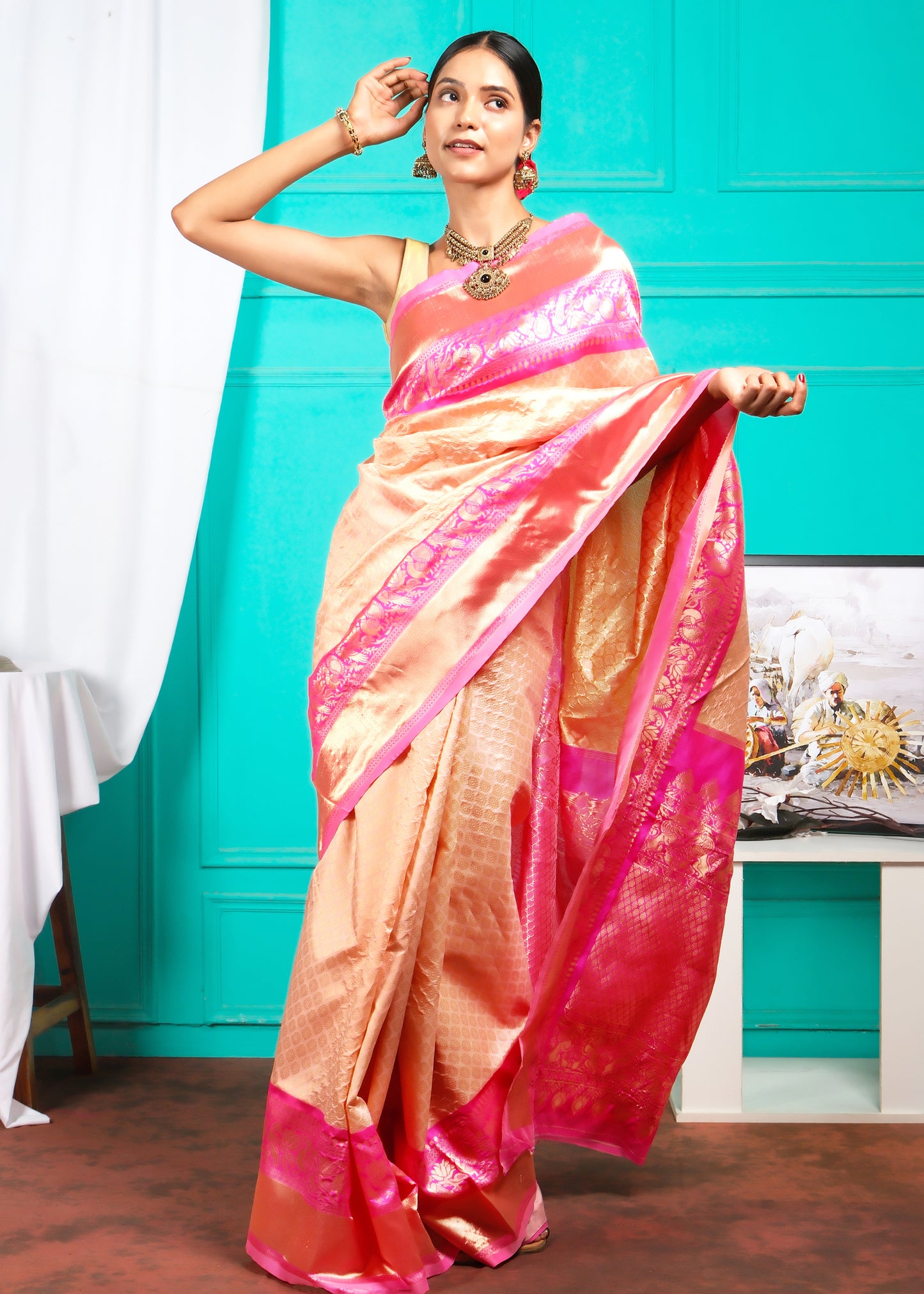 Woman flaunting the traditional elegance of a peach and pink silk saree with intricate gold details, perfect for cultural events