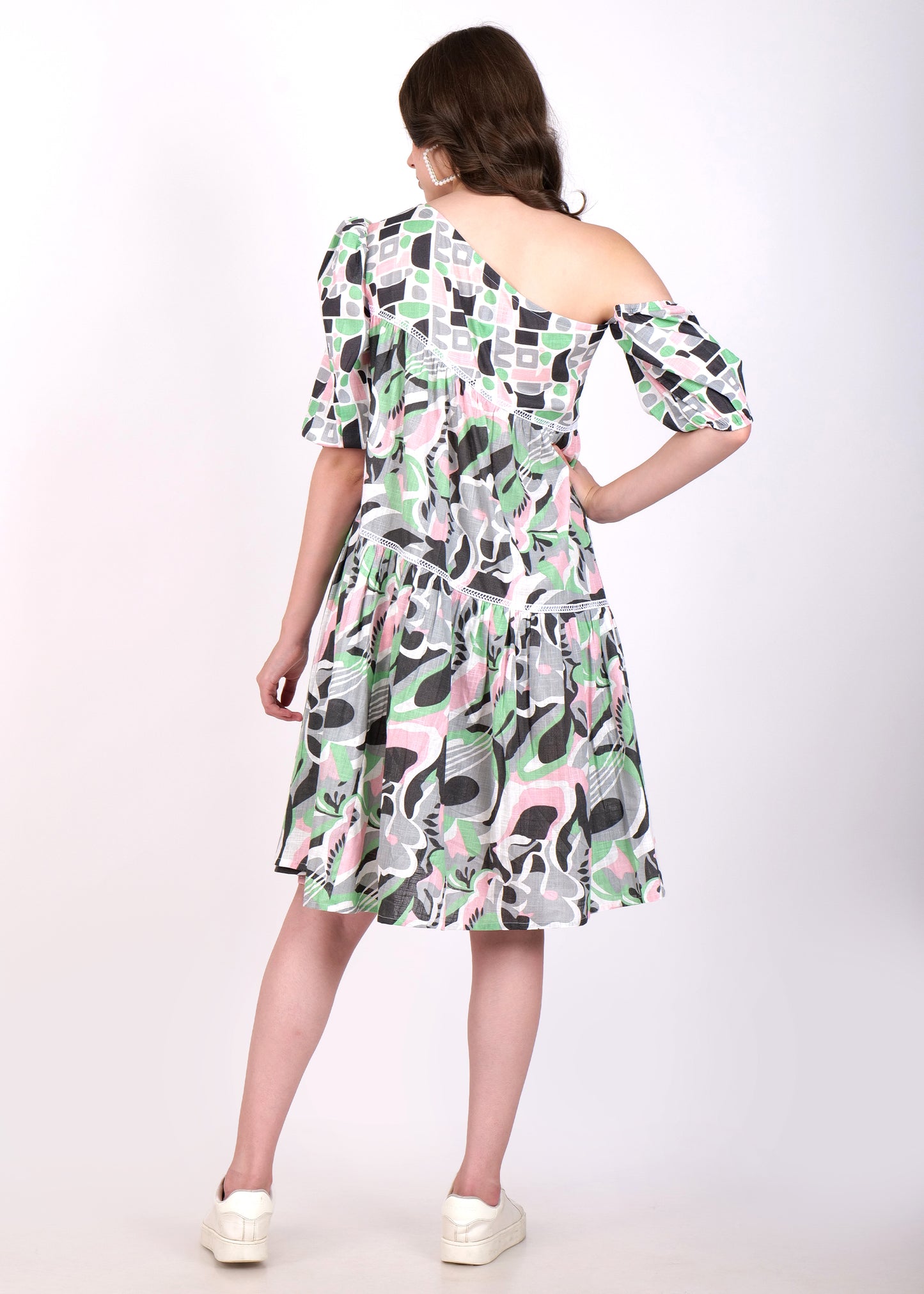 Rear view of a woman showcasing the back of a one-shoulder geometric patterned dress.