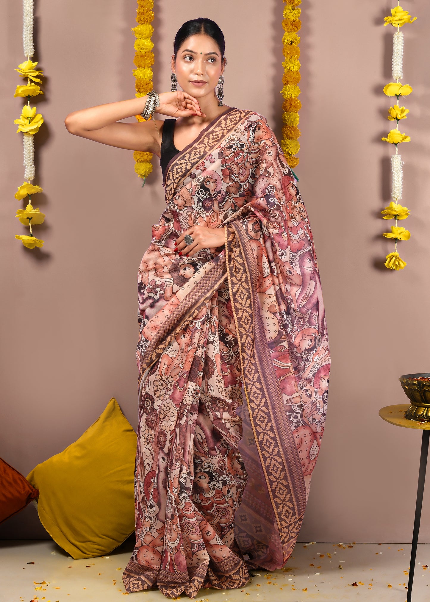 "Elegant woman posing in a saree with mythological patterns and detailed pallu, styled with traditional jewelry."