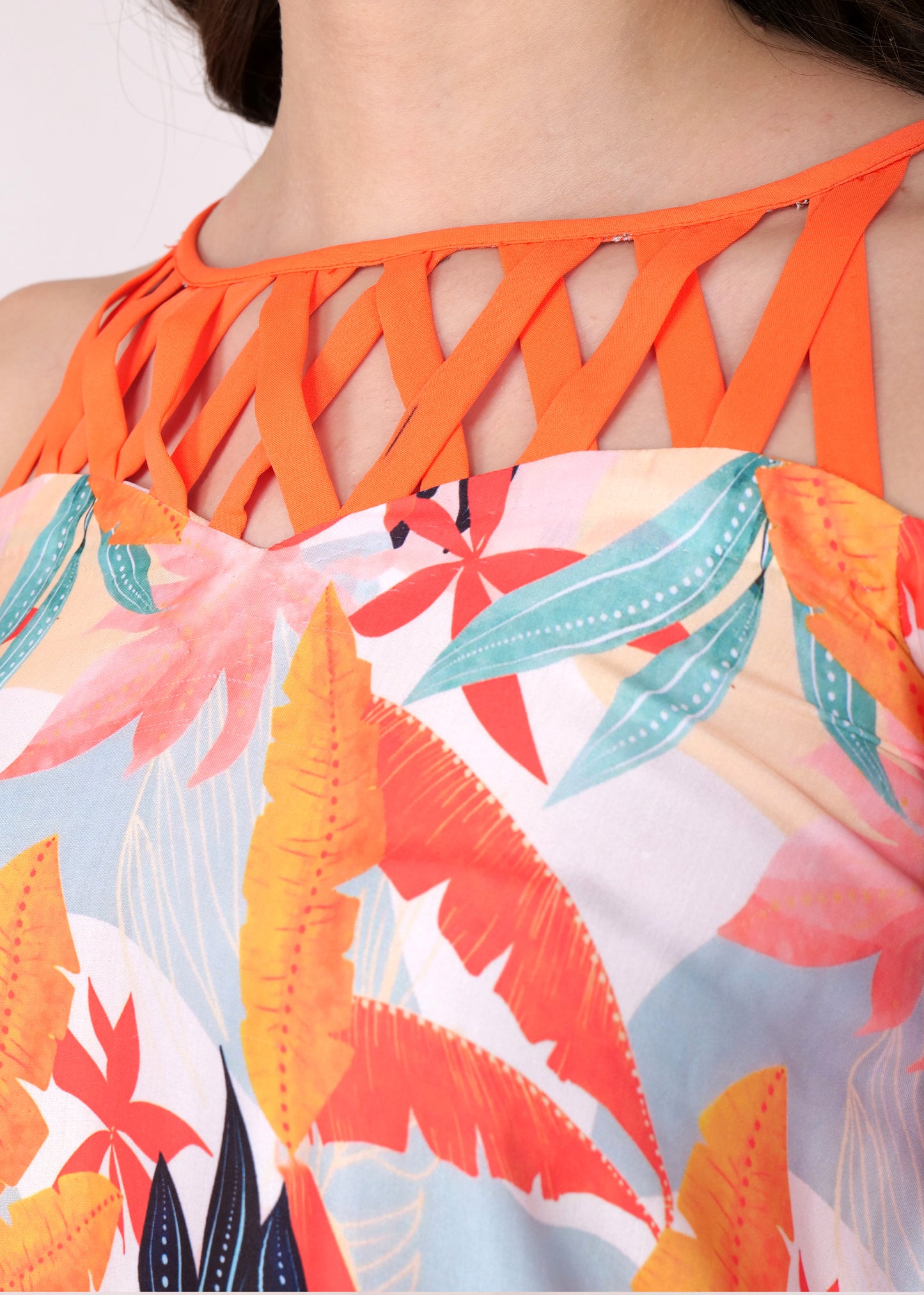 Close-up of the orange criss-cross neckline and tropical leaf pattern on a summer dress.