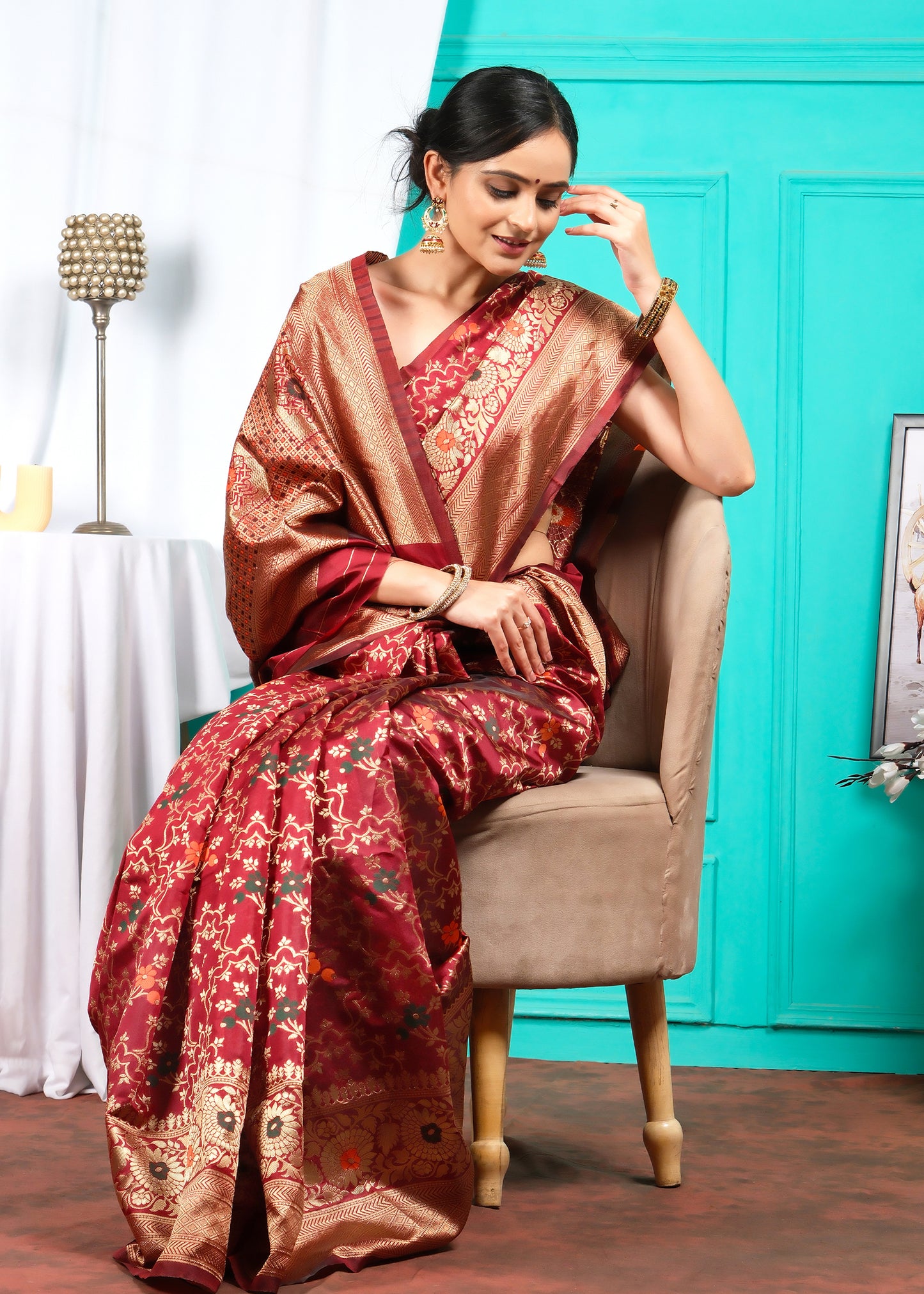 Elegant Indian woman seated in a red Banarasi saree with luxurious zari work, exuding grace and tradition