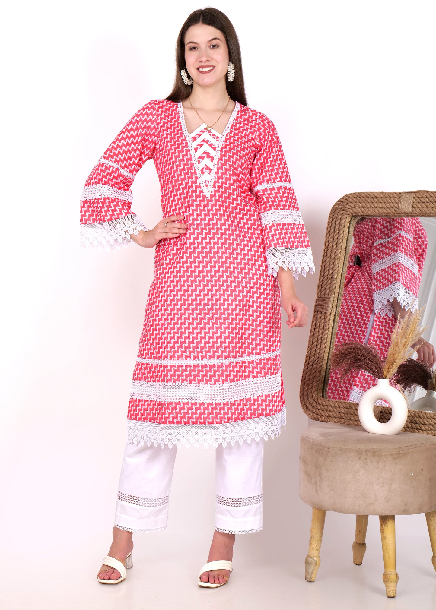 Woman posing confidently in front of a mirror, dressed in a red zigzag kurta with lace trim, styled with white straight pants.