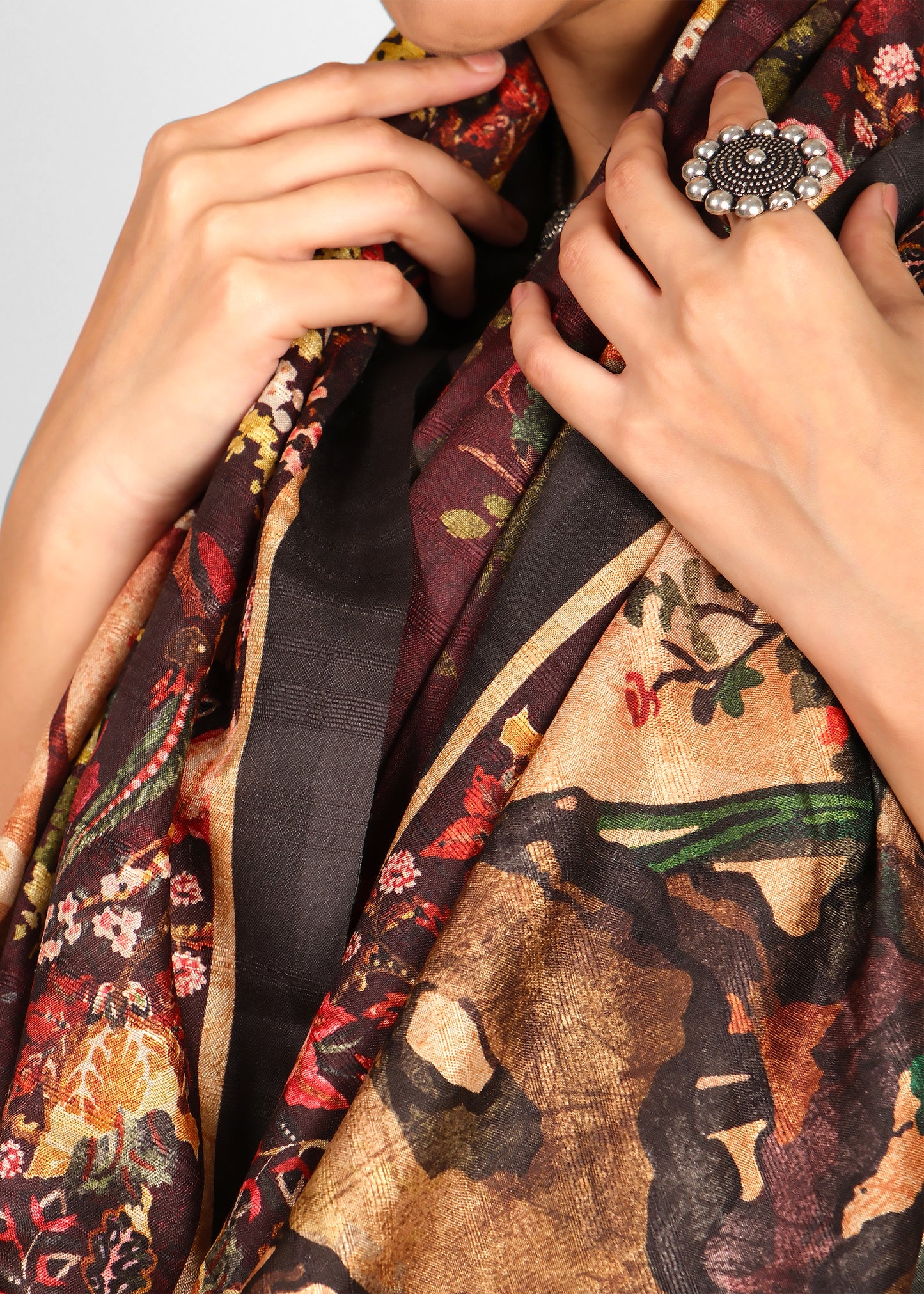 Detailed close-up of floral and nature motifs on a maroon saree, highlighting intricate craftsmanship and luxury fabric