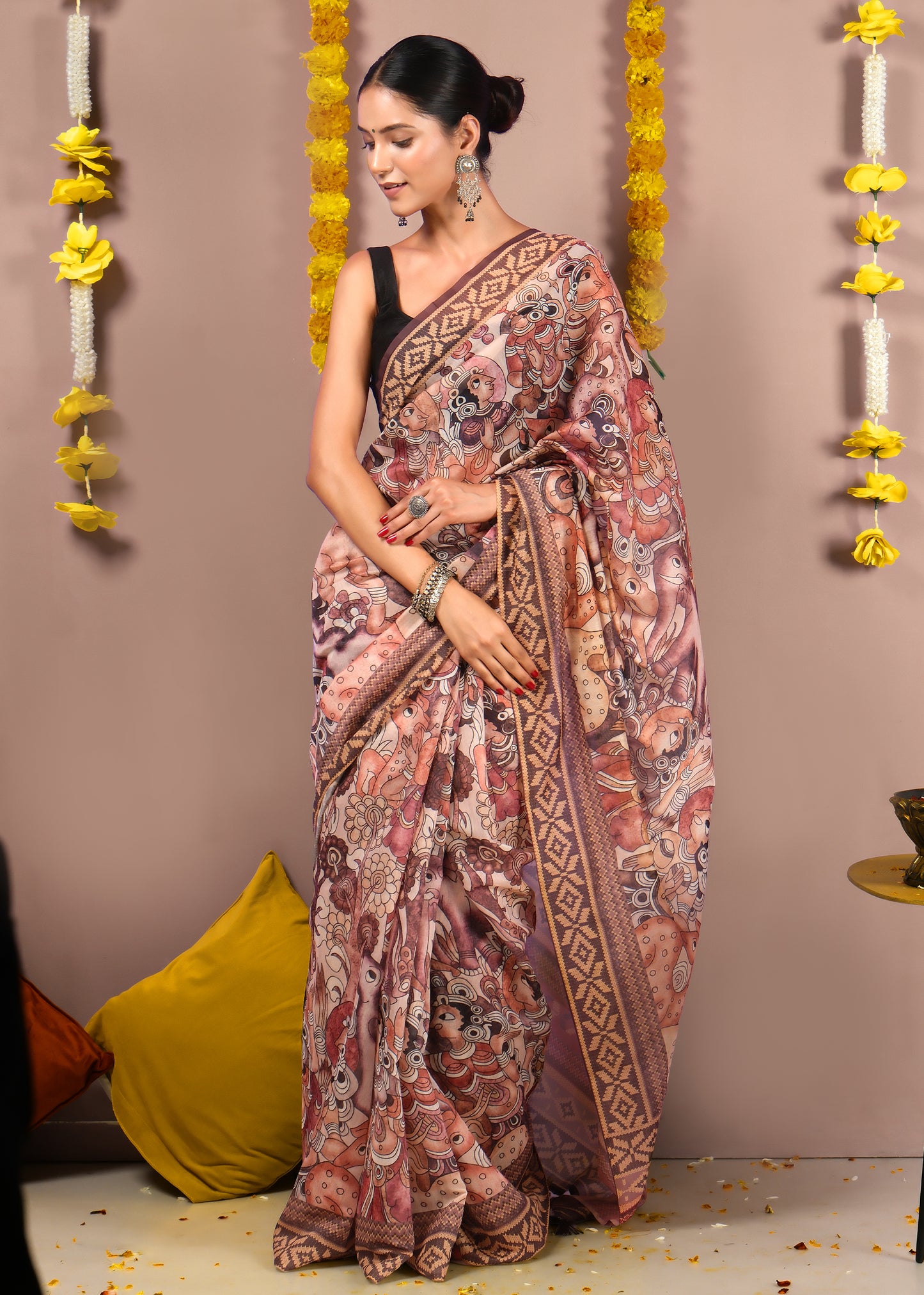 "Close-up of a seated woman in a saree with detailed artwork of mythological figures, styled with silver accessories."