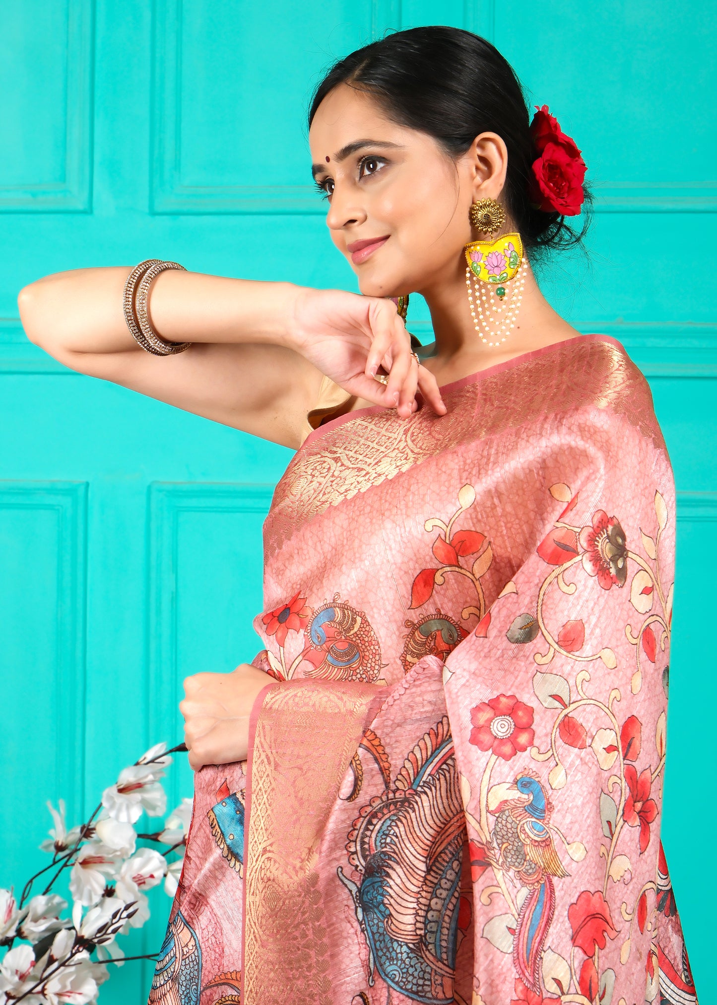 Close-up of the pallu of a pink silk saree, displaying intricate peacock and floral designs, perfect for festive and traditional occasions.