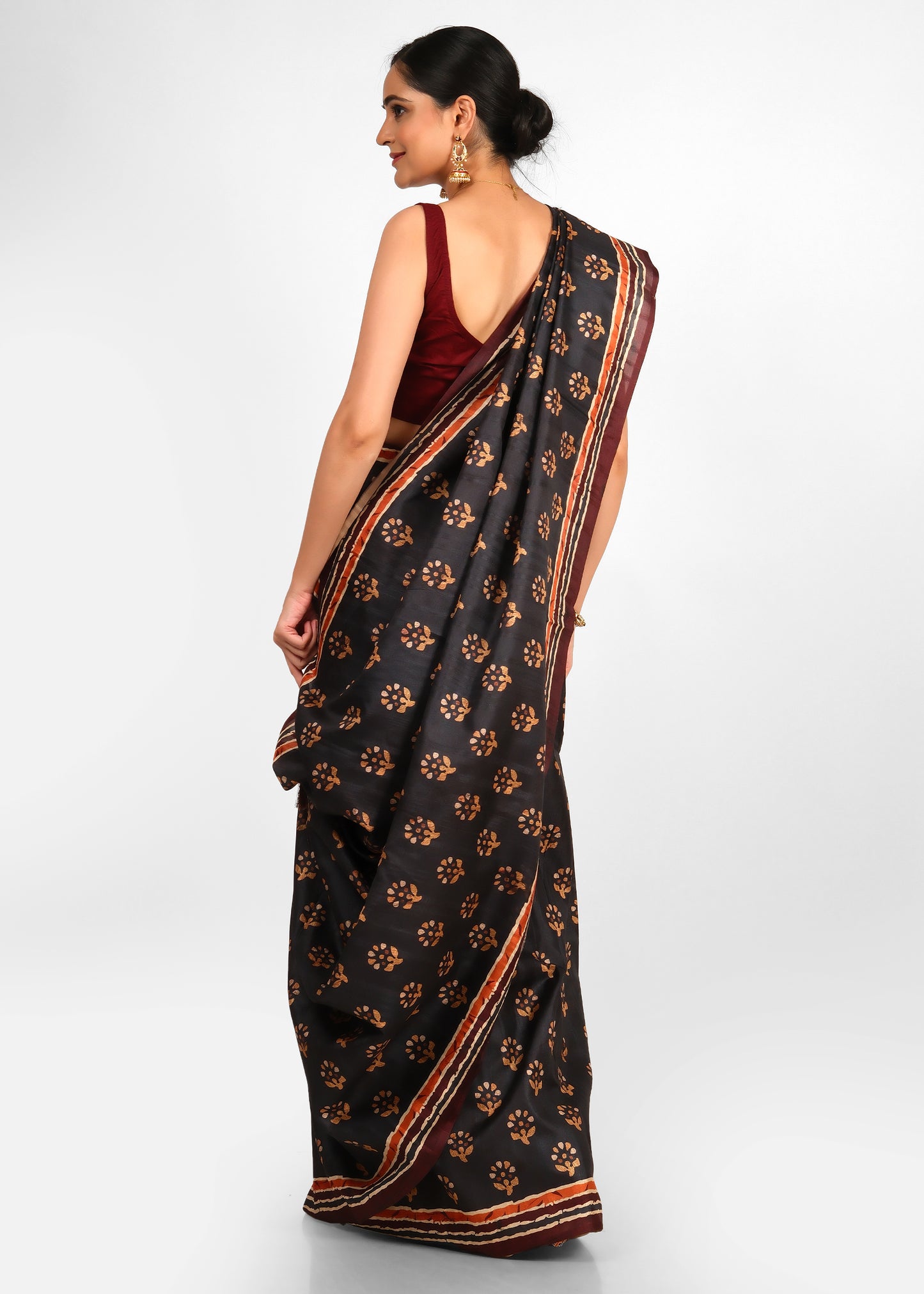 Rear view of a woman wearing a black floral printed saree with maroon blouse, showcasing the beautiful draping of the saree