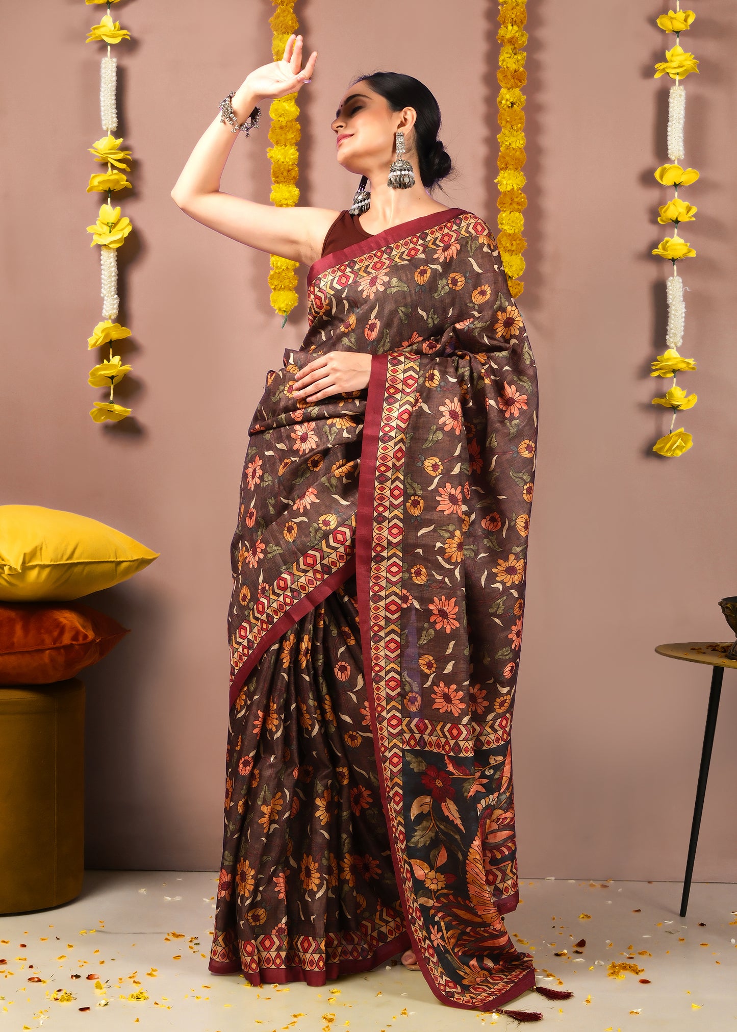 Woman exuding grace in a brown saree with floral and geometric patterns, posing for a festive photoshoot.