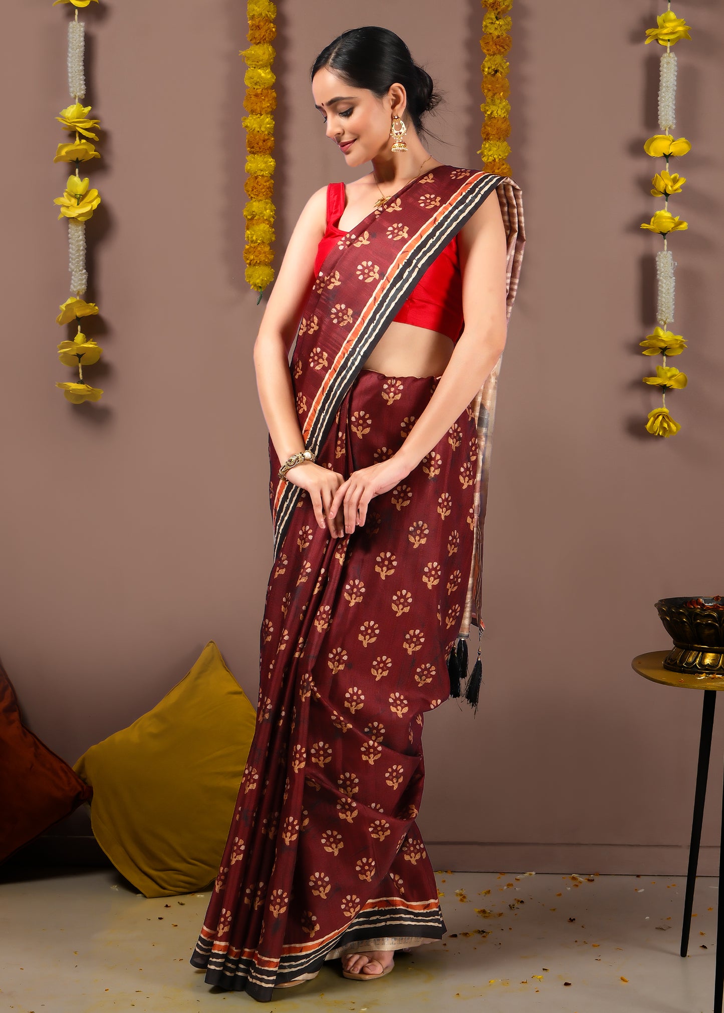 Woman gracefully draped in a maroon Kalamkari art silk saree with floral motifs and black border.