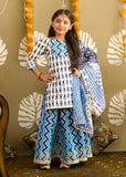 A young girl wearing a vibrant blue and white ethnic outfit, with intricate geometric patterns and a matching dupatta, standing in a traditional festive setting.