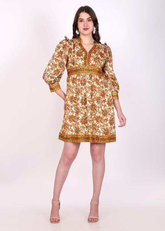 A woman wearing a vintage-inspired boho floral dress with intricate orange and green paisley patterns. The dress features a deep V-neckline and three-quarter puff sleeve