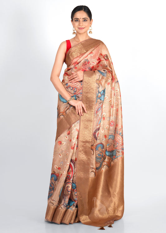 Woman draped in a beige saree with intricate peacock and floral motifs, styled for a traditional festive look.