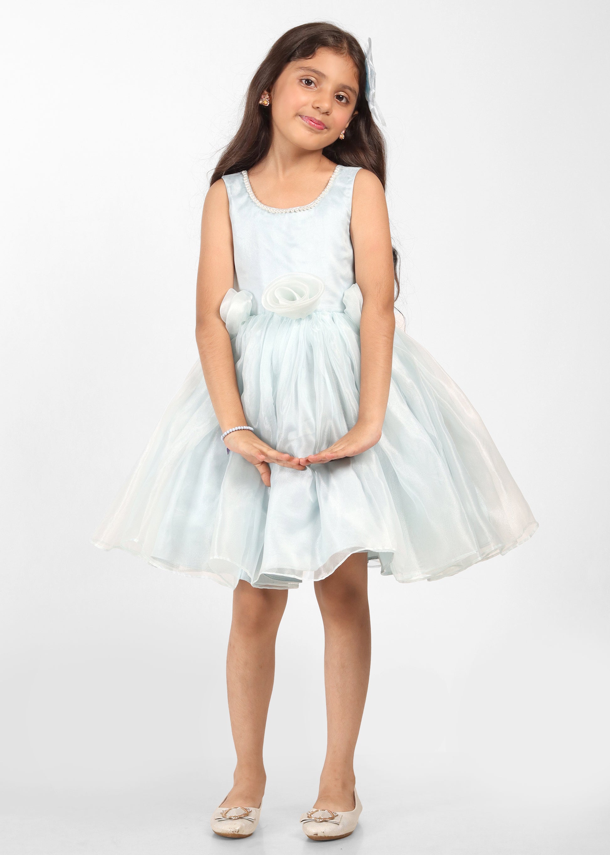 Young girl dressed in a floral blue dress with stunning bow details on the shoulders, perfect for kids' fashion shoots.