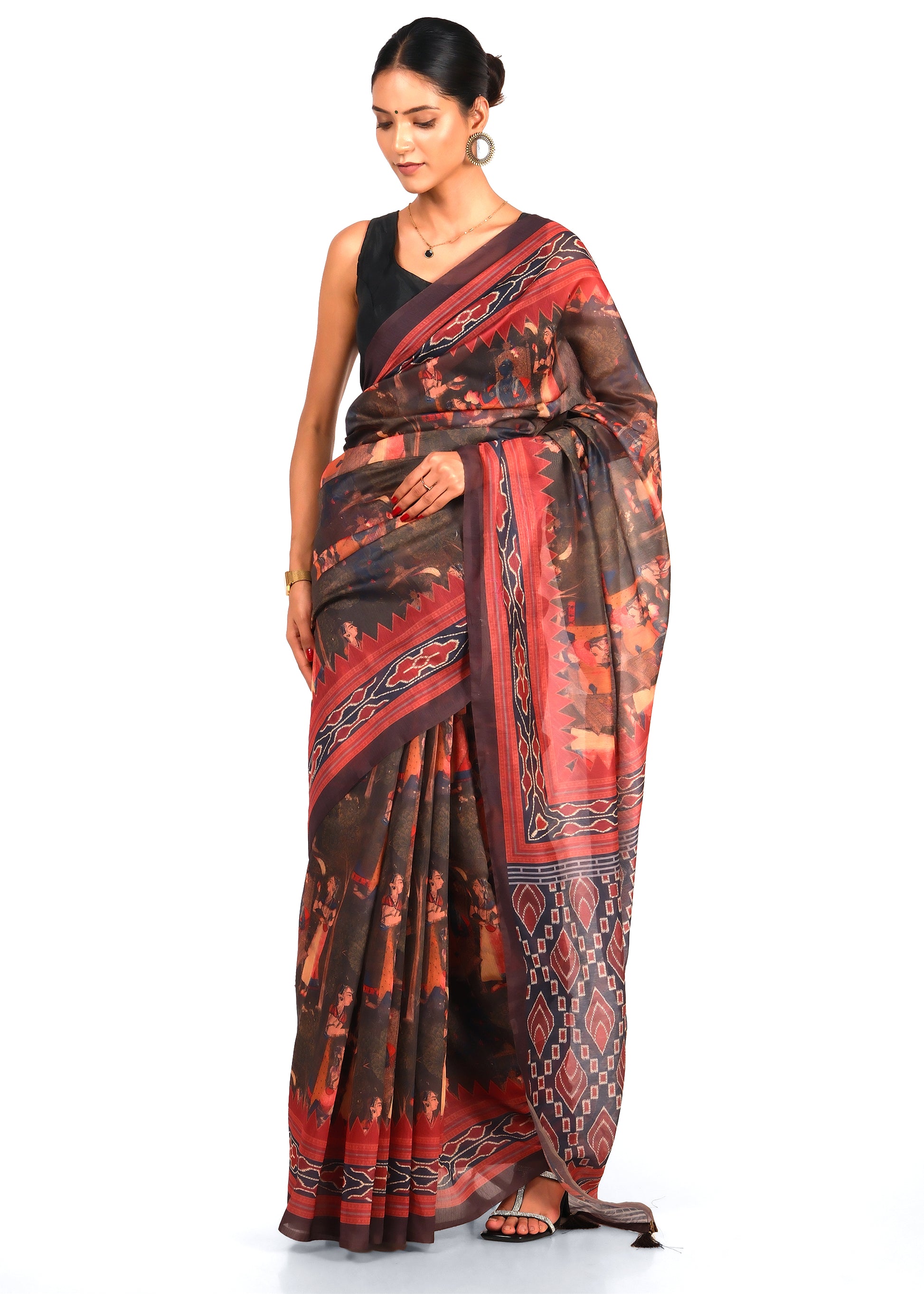 Woman wearing a red and black saree with intricate geometric and cultural patterns, styled elegantly for a festive event.