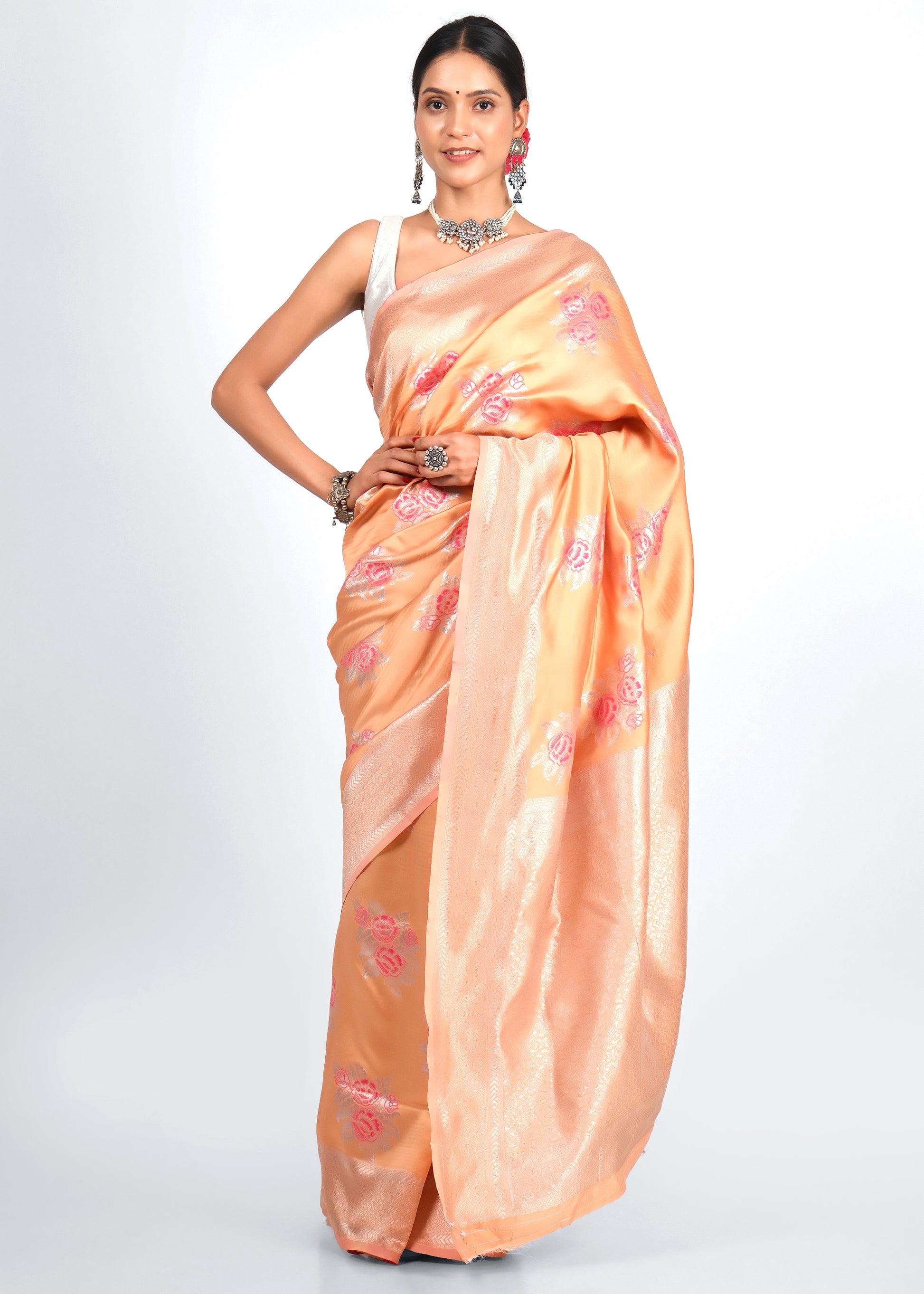 Model in a peach-colored Banarasi silk saree with intricate pink floral embroidery and silver zari work, perfect for traditional wear