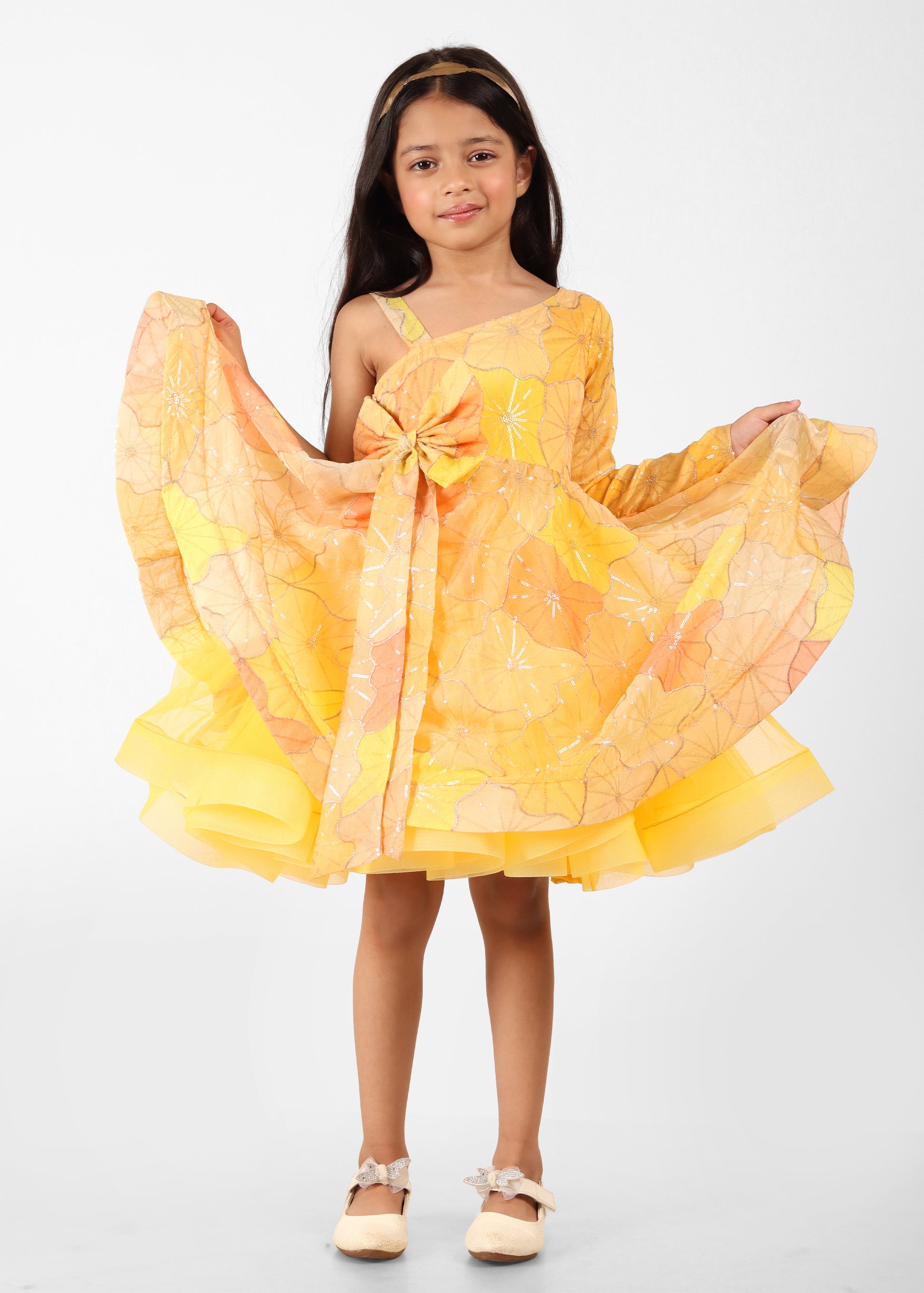 "Adorable girl wearing a yellow floral print one-shoulder dress with a bow, ideal for special occasions or festive events."