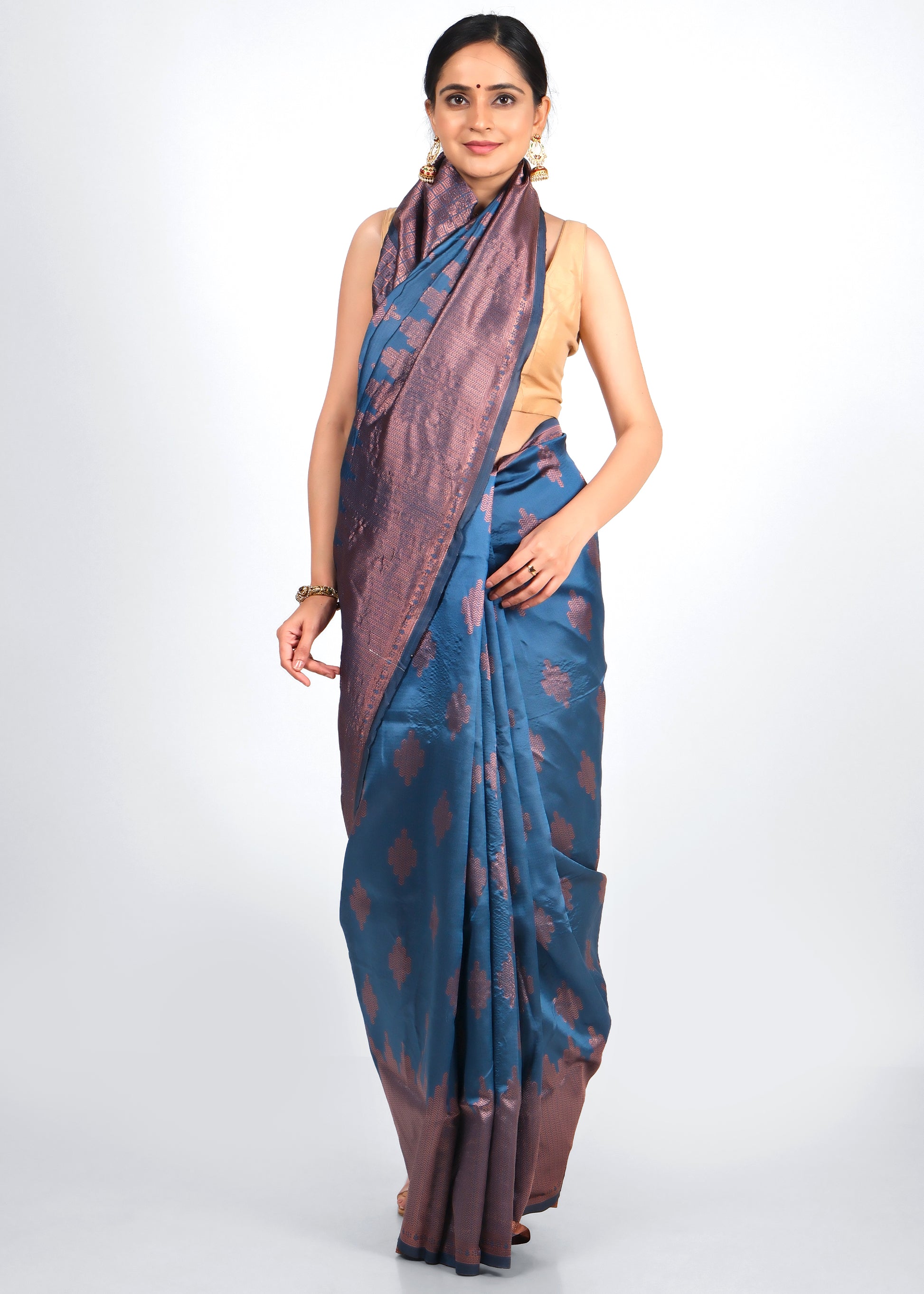 Model wearing a royal blue and copper woven silk saree with intricate motifs, paired with traditional gold earrings