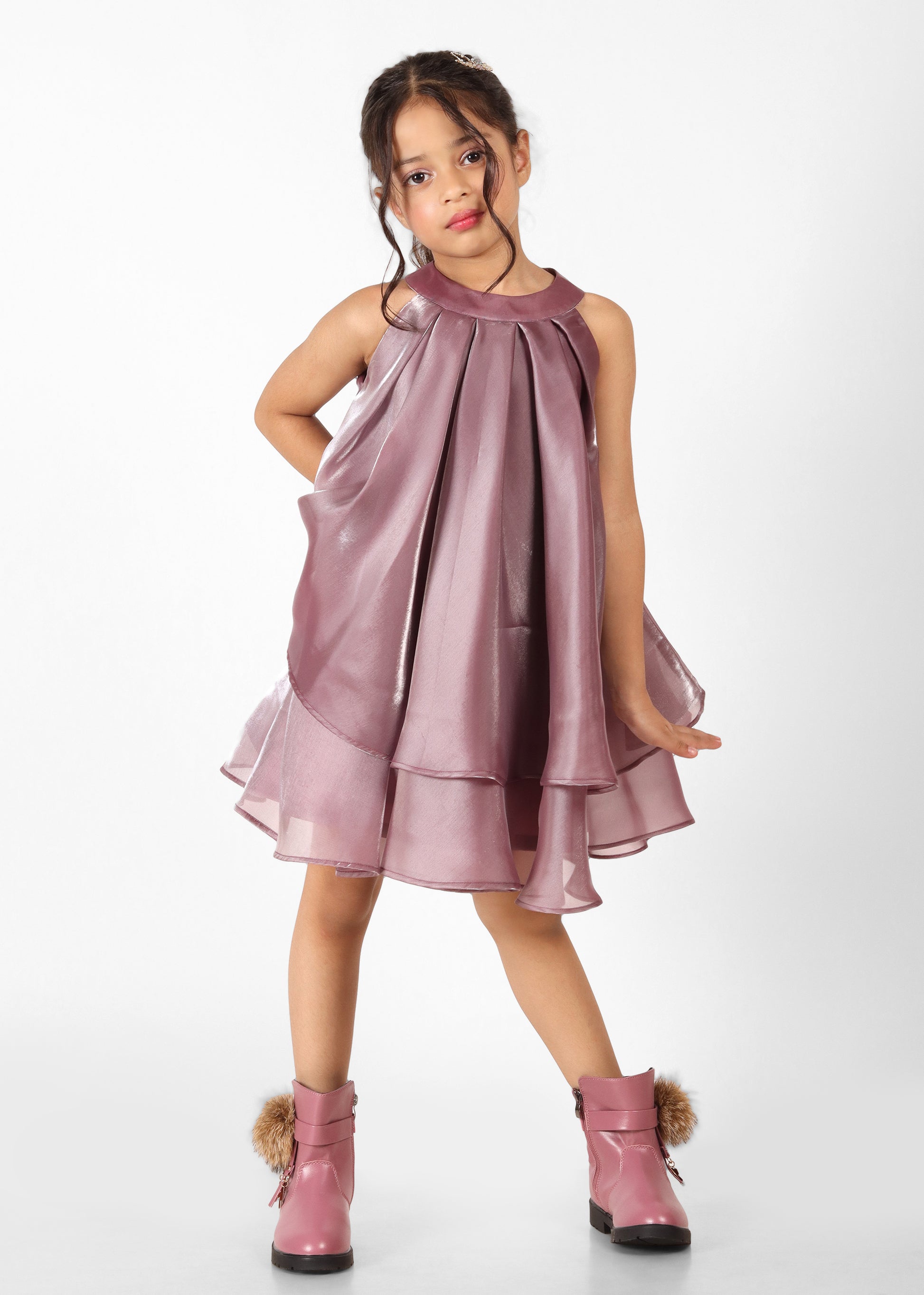 Young girl posing confidently in a shiny mauve dress paired with pink boots, ideal for a stylish and trendy kids' fashion look