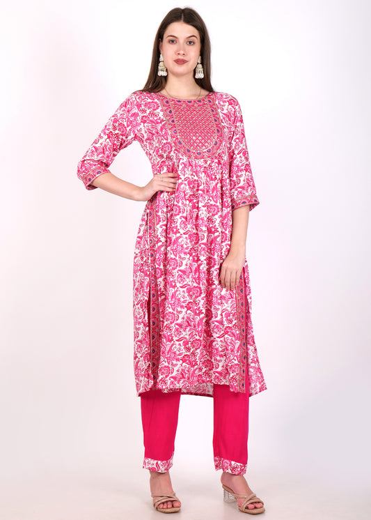 Woman wearing a pink floral printed kurta with intricate embroidery and white trousers, standing confidently.