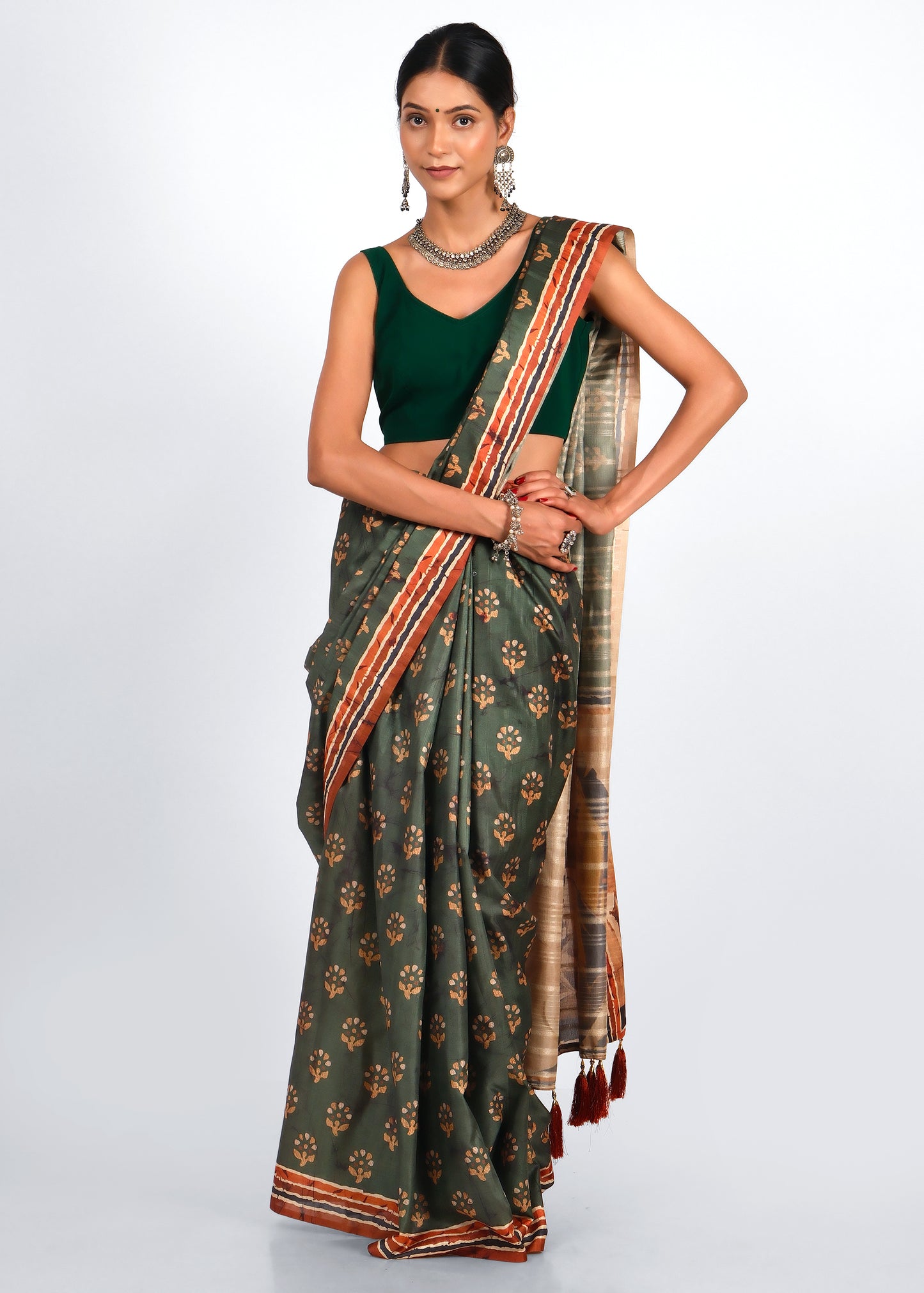 Model wearing a green designer saree with golden motifs, featuring a contrasting striped border
