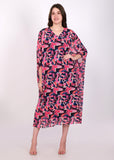 Model posing in a vibrant pink and purple abstract kaftan dress with flowing sleeves and a relaxed fit