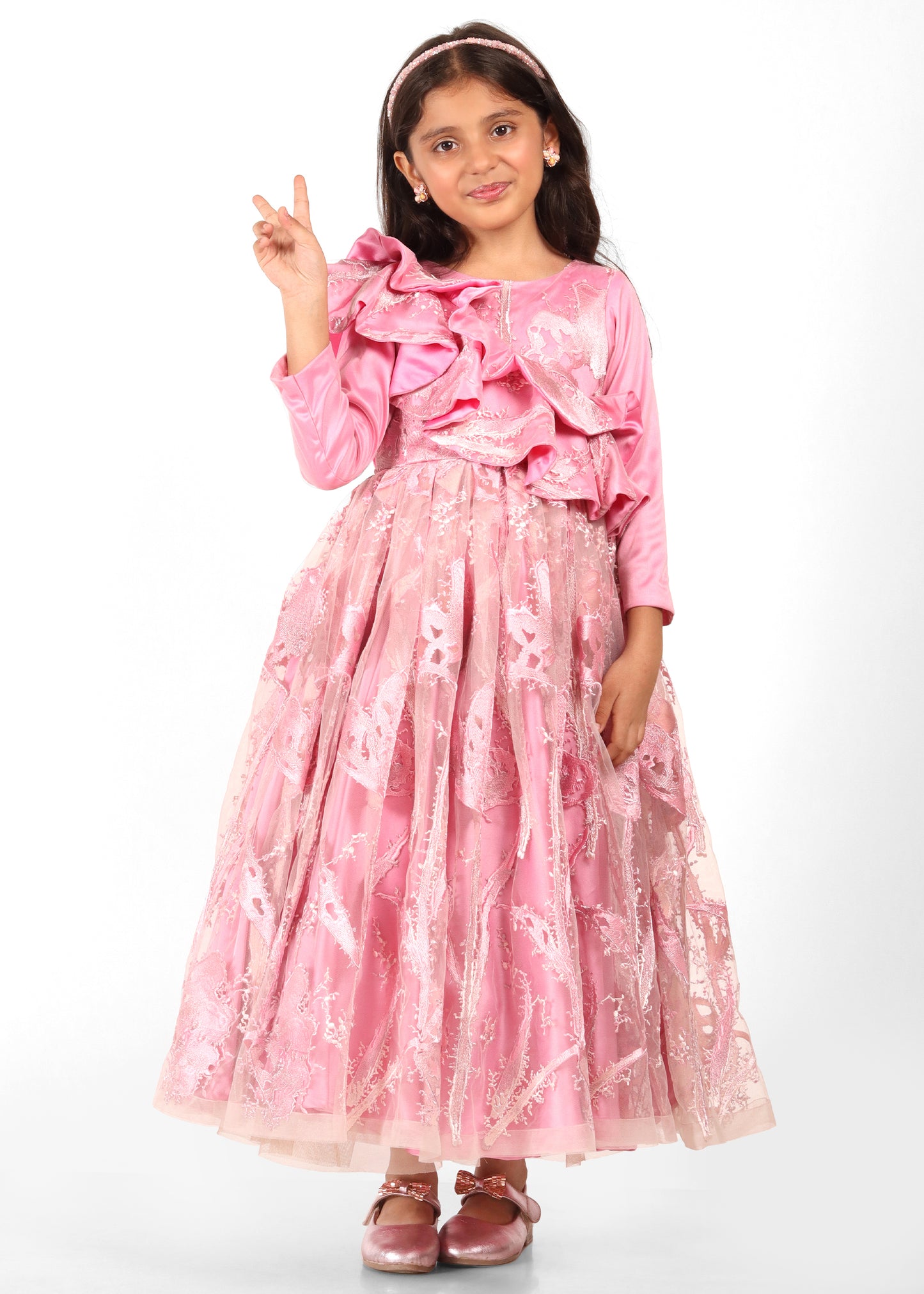 Girl posing in a long pink gown with detailed lace and ruffles, exuding elegance and style.