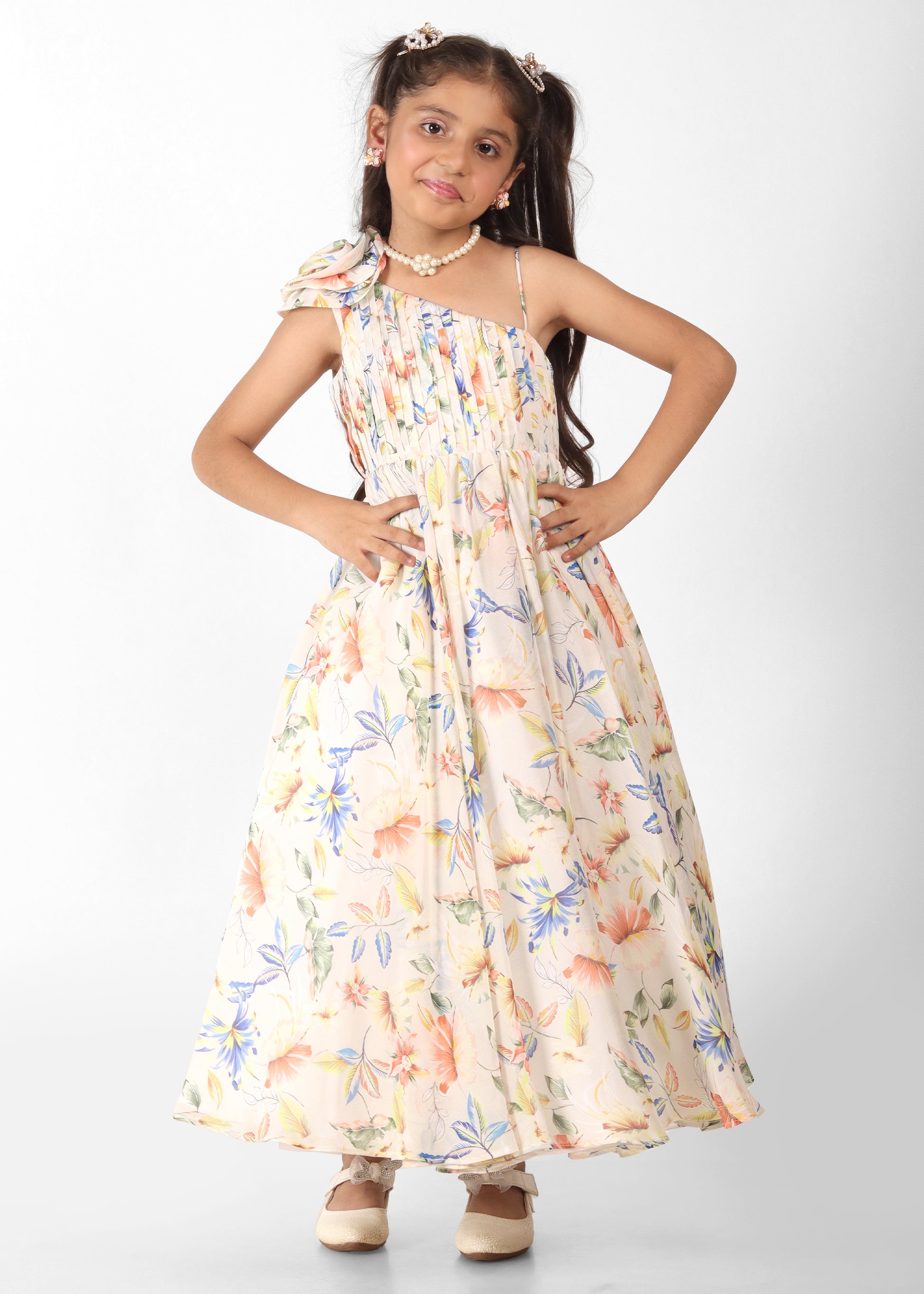 Girl wearing a floral printed off-shoulder gown with colorful flowers and a pleated bodice, holding a stuffed tiger